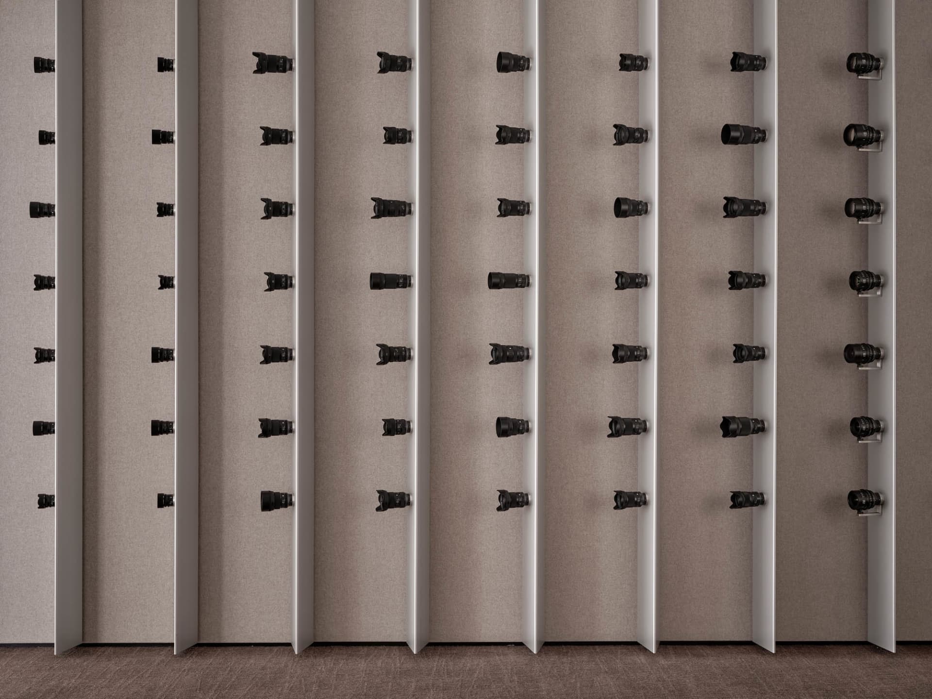 A row of black objects mounted on a wall in a neat and organized manner, possibly in an art gallery or museum setting
