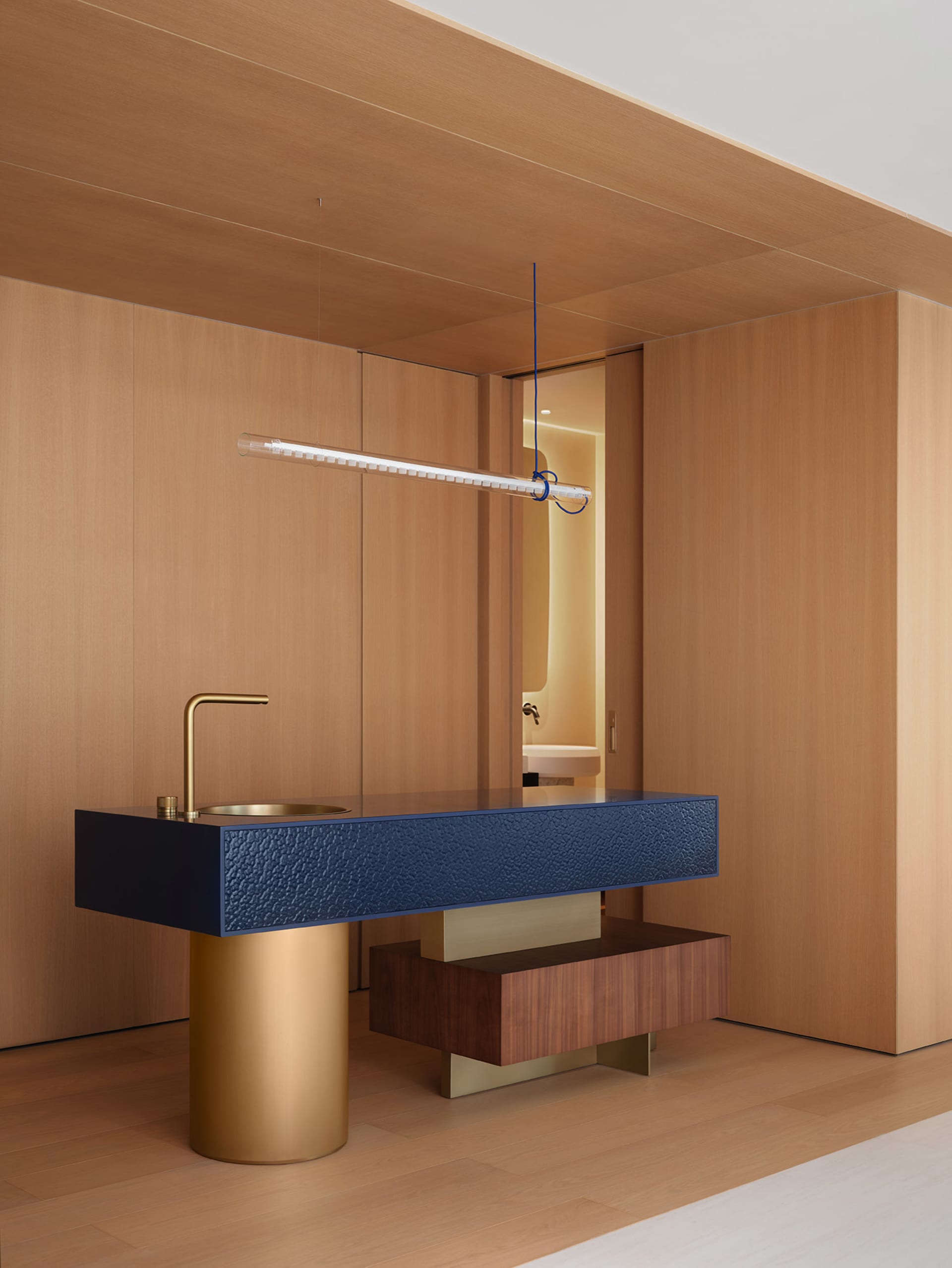 Modern bathroom with a marble sink, wooden cabinet, and gold faucet, featuring a clean and minimalist style with warm lighting