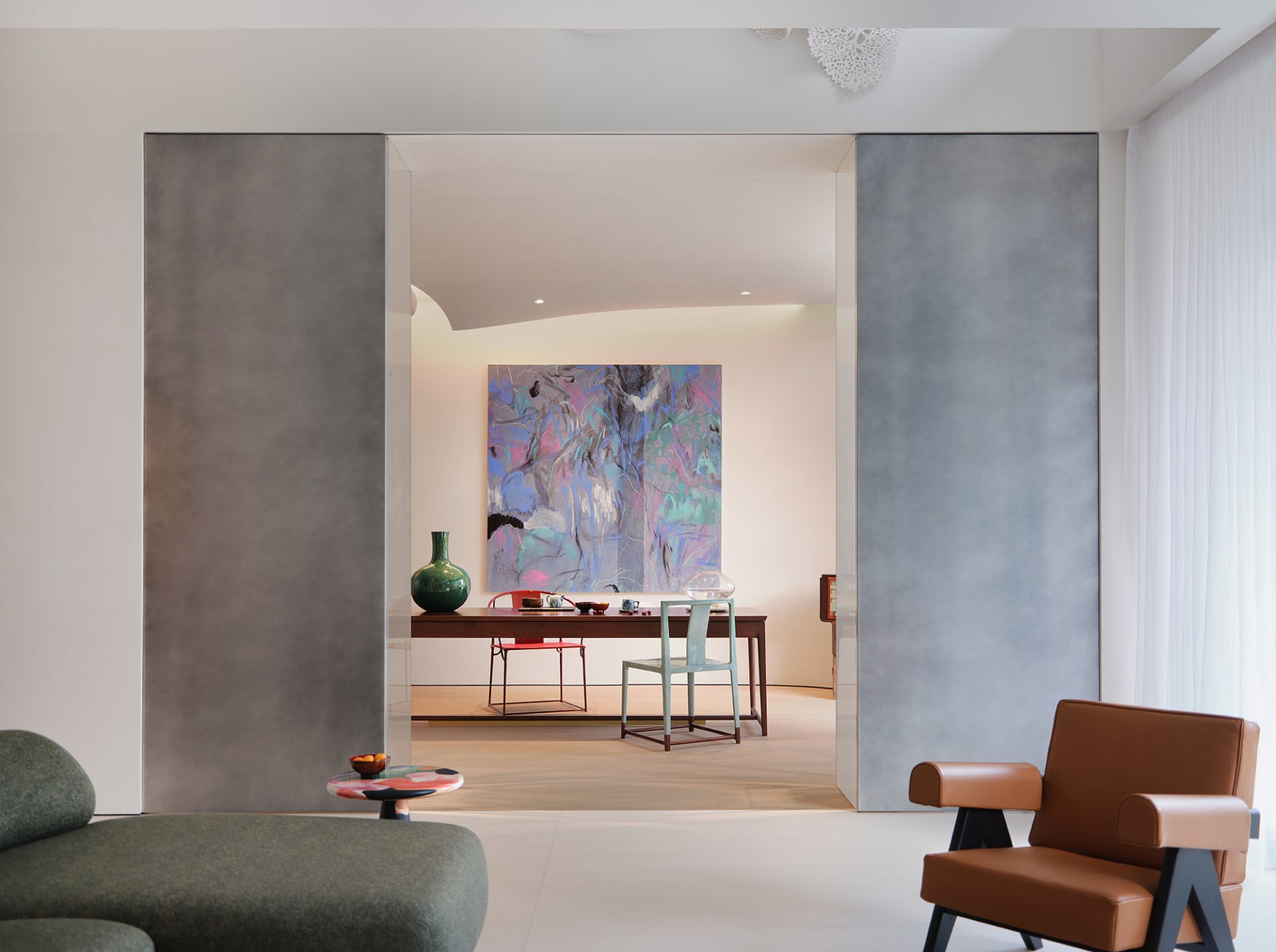 Modern living area with a large painting, two chairs, a dining table, and a vase, featuring clean lines and minimalistic elements