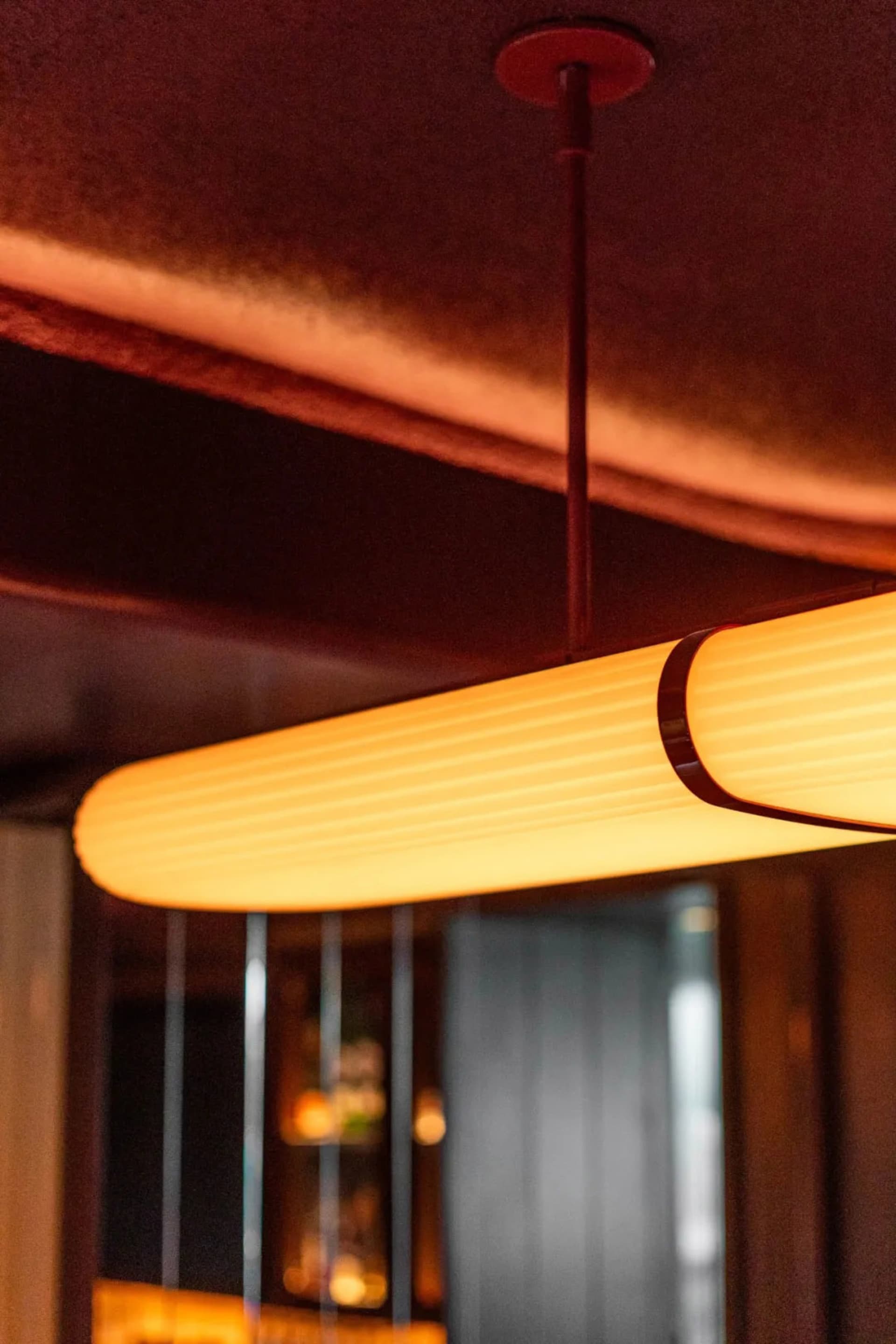 A warm and inviting interior space with a wooden light fixture, bottles, and a cup, illuminated by the light source