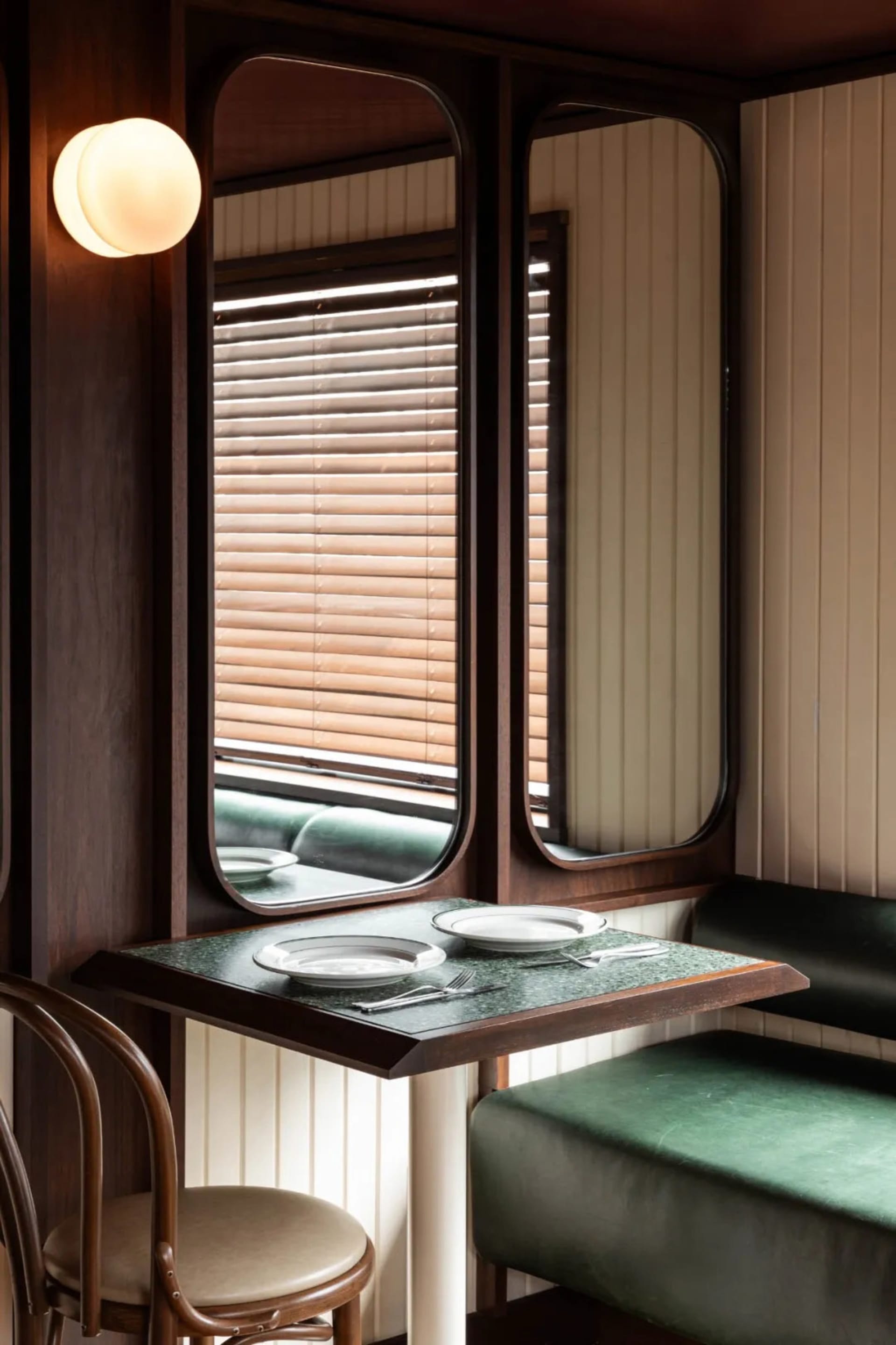 A dining area in a restaurant with a wooden table surrounded by chairs, set with plates, cutlery, and bowls, creating a warm and inviting atmosphere
