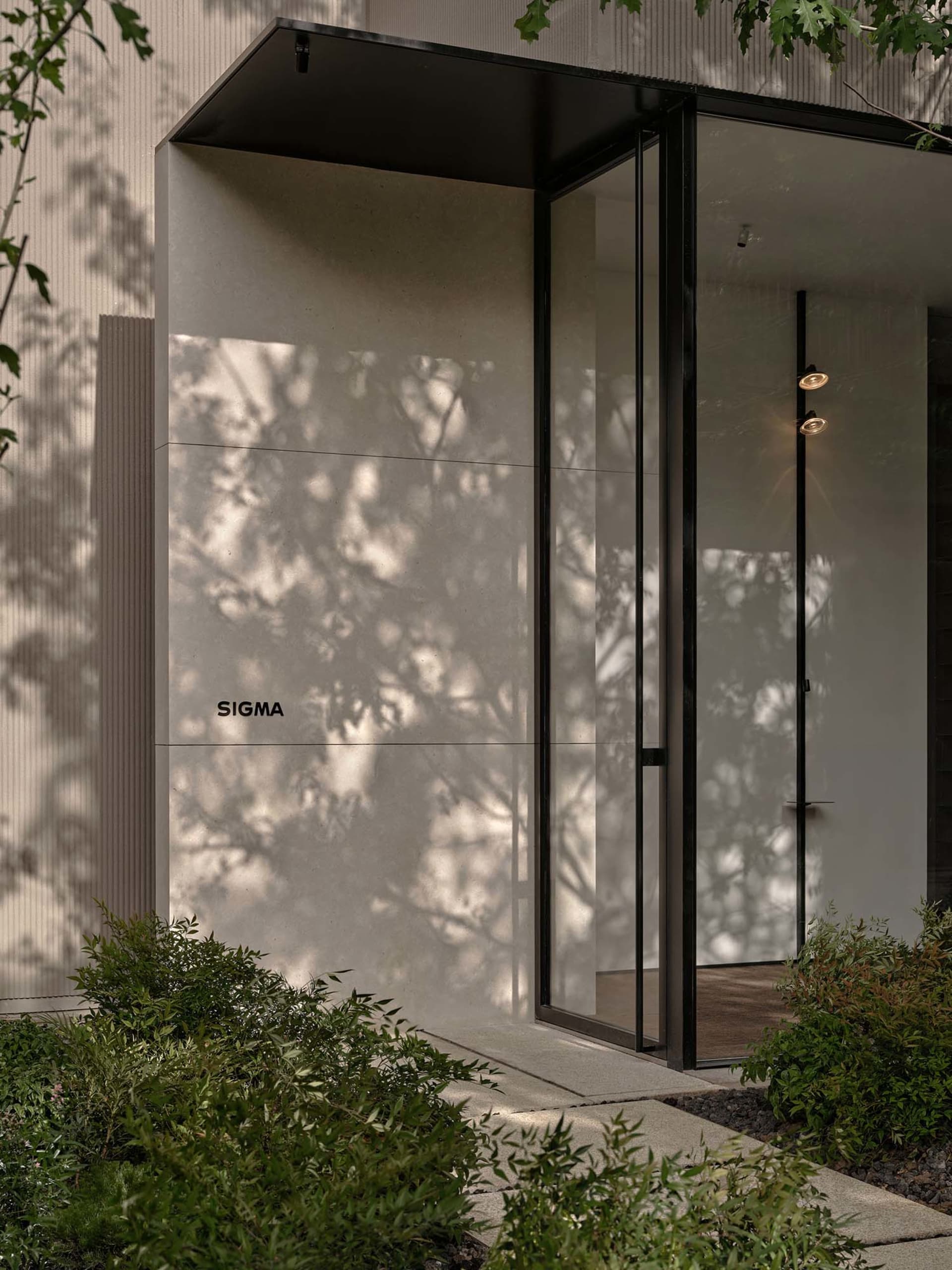 A modern indoor space with a glass door and window, featuring clean lines and minimalistic design elements, with sunlight streaming through the windows