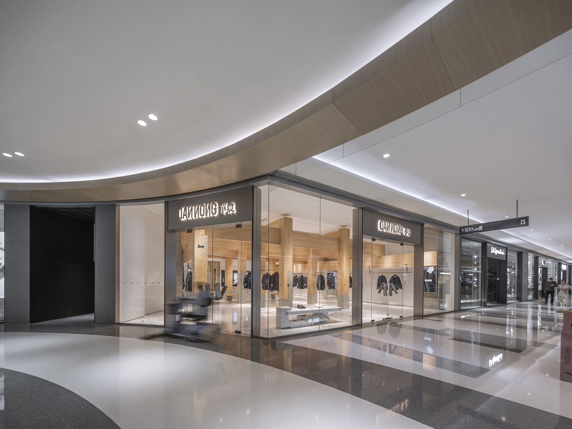 A modern retail space with a large storefront featuring a curved glass wall and mannequins showcasing clothing items on display