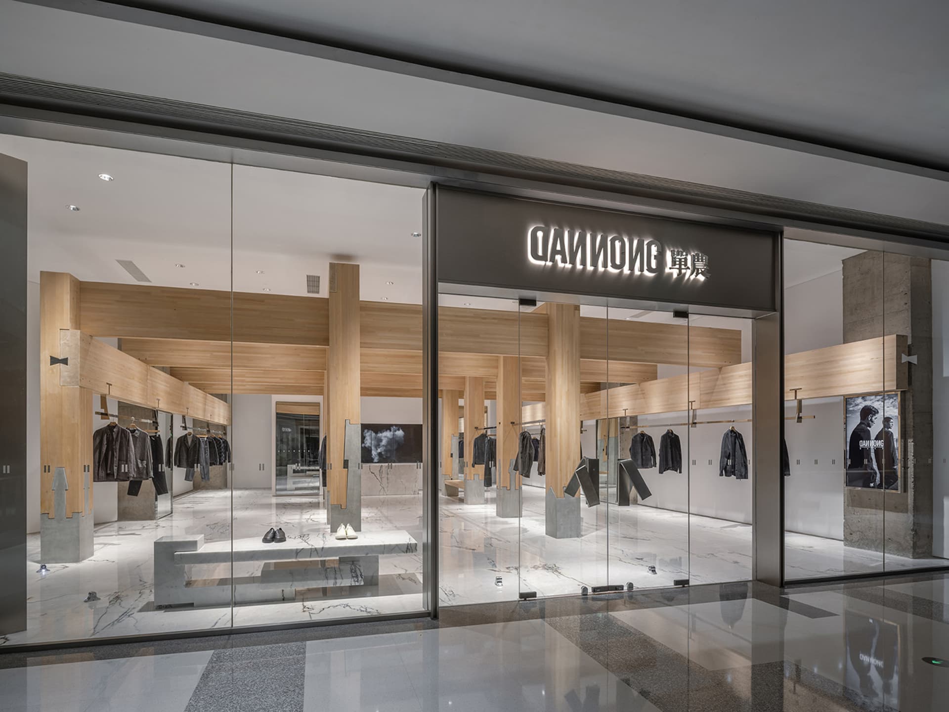 Modern storefront with a large glass window showcasing mannequins in black clothing, set against a clean and minimalist background