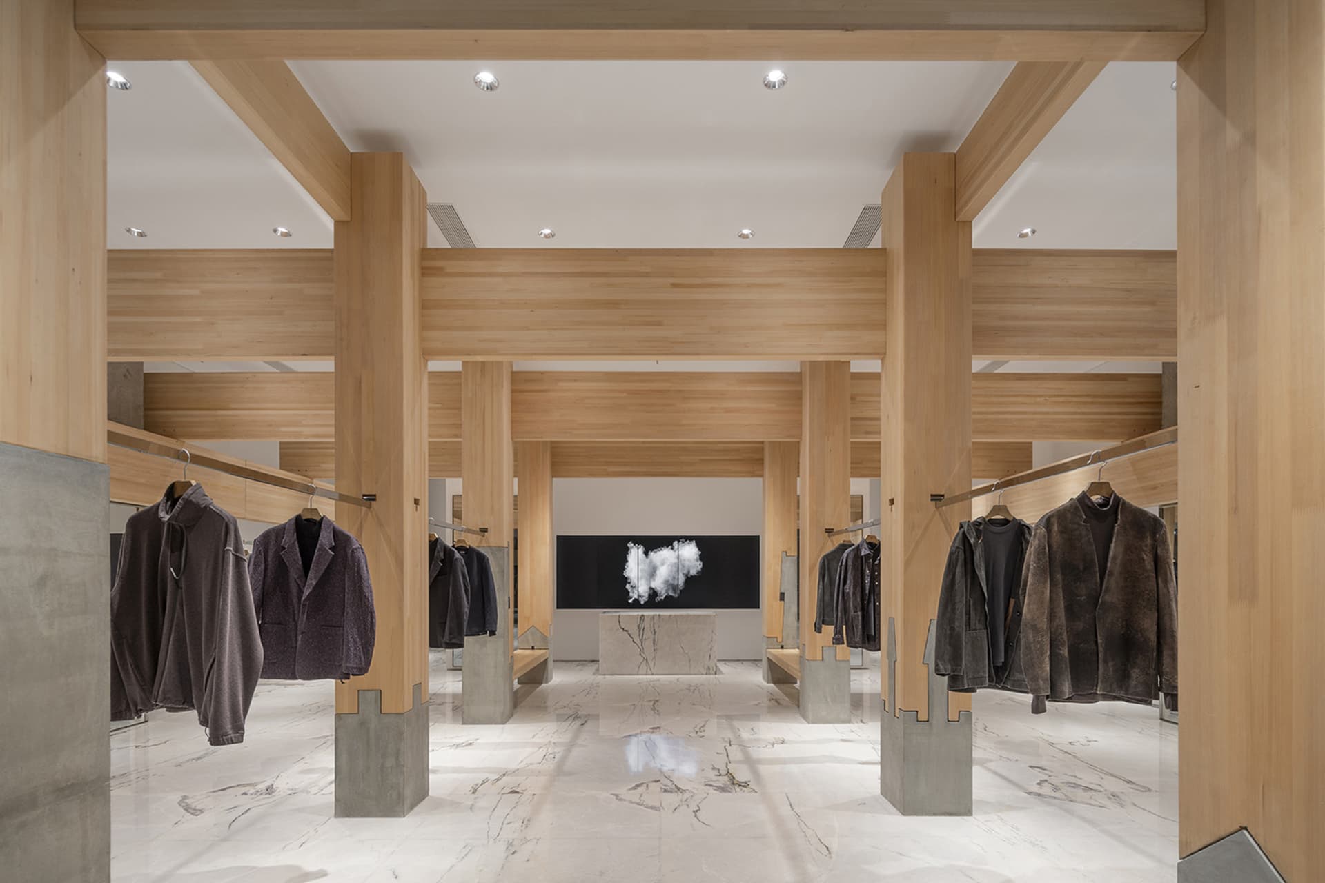 A well-lit retail space with wooden walls and floors, featuring a variety of clothing items on display
