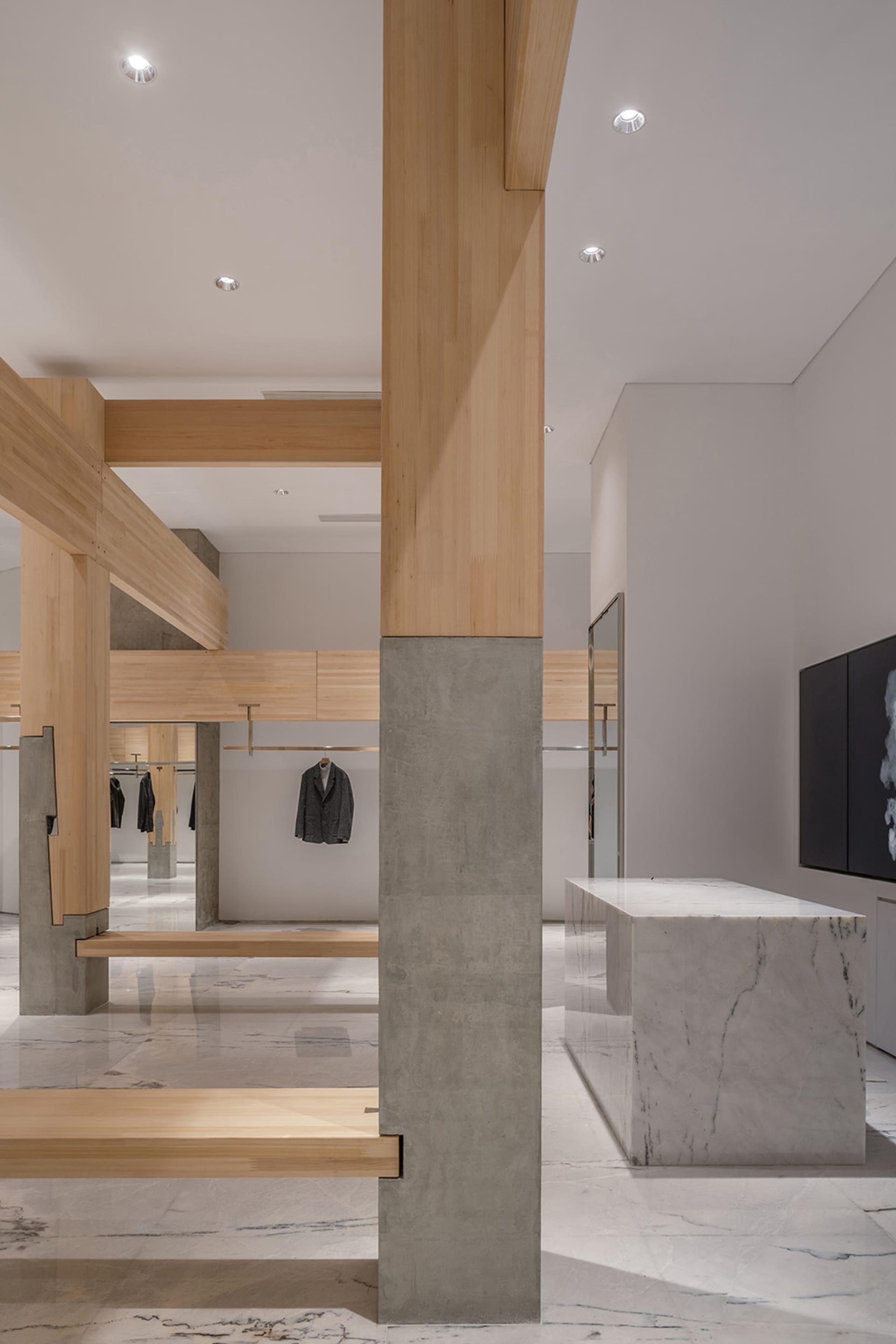 Open modern space with a concrete floor, marble countertop, and hanging clothes on display, creating a clean and minimalistic atmosphere