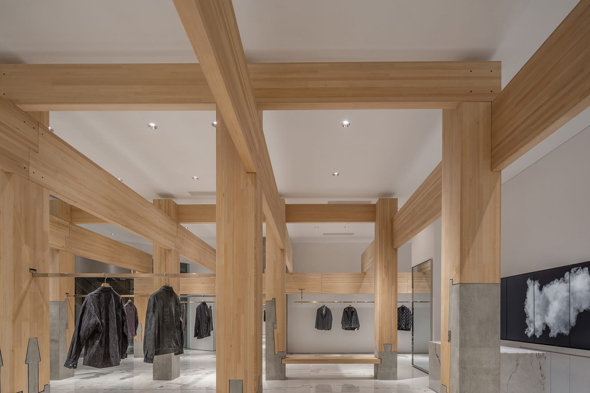 A large open space with wooden beams and columns, displaying vintage garments on clothes racks, in a modern space with a blend of traditional materials
