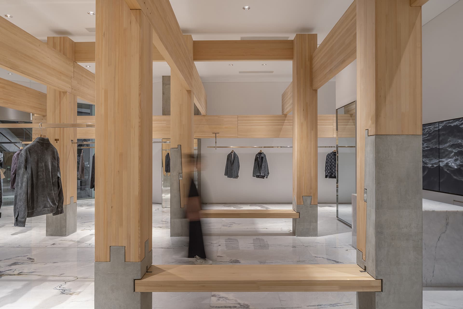 Modern retail space with wooden walls and floors, featuring mannequins dressed in various clothing items in a well-lit and inviting atmosphere