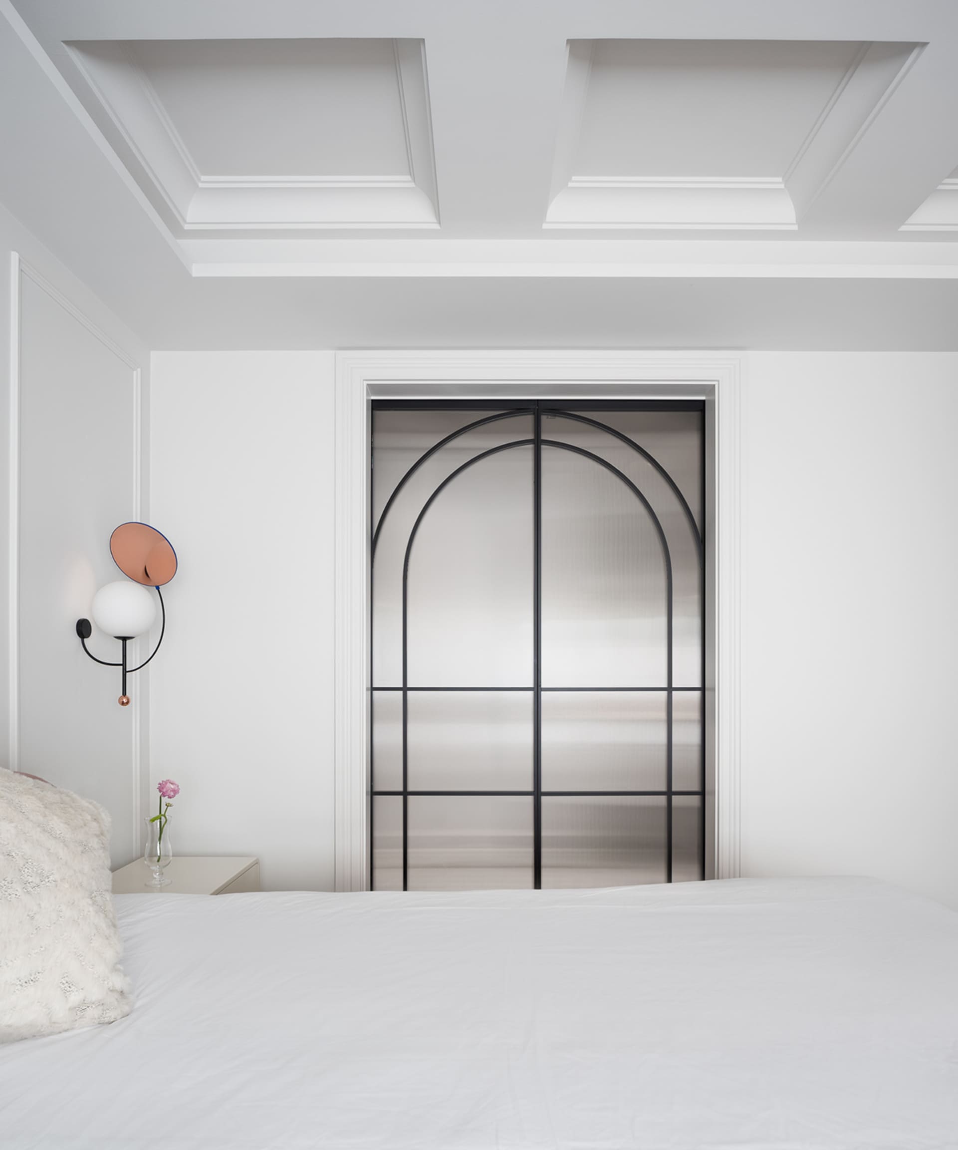 A calm and inviting bedroom with a white bed, metal-framed window, and white plaster walls