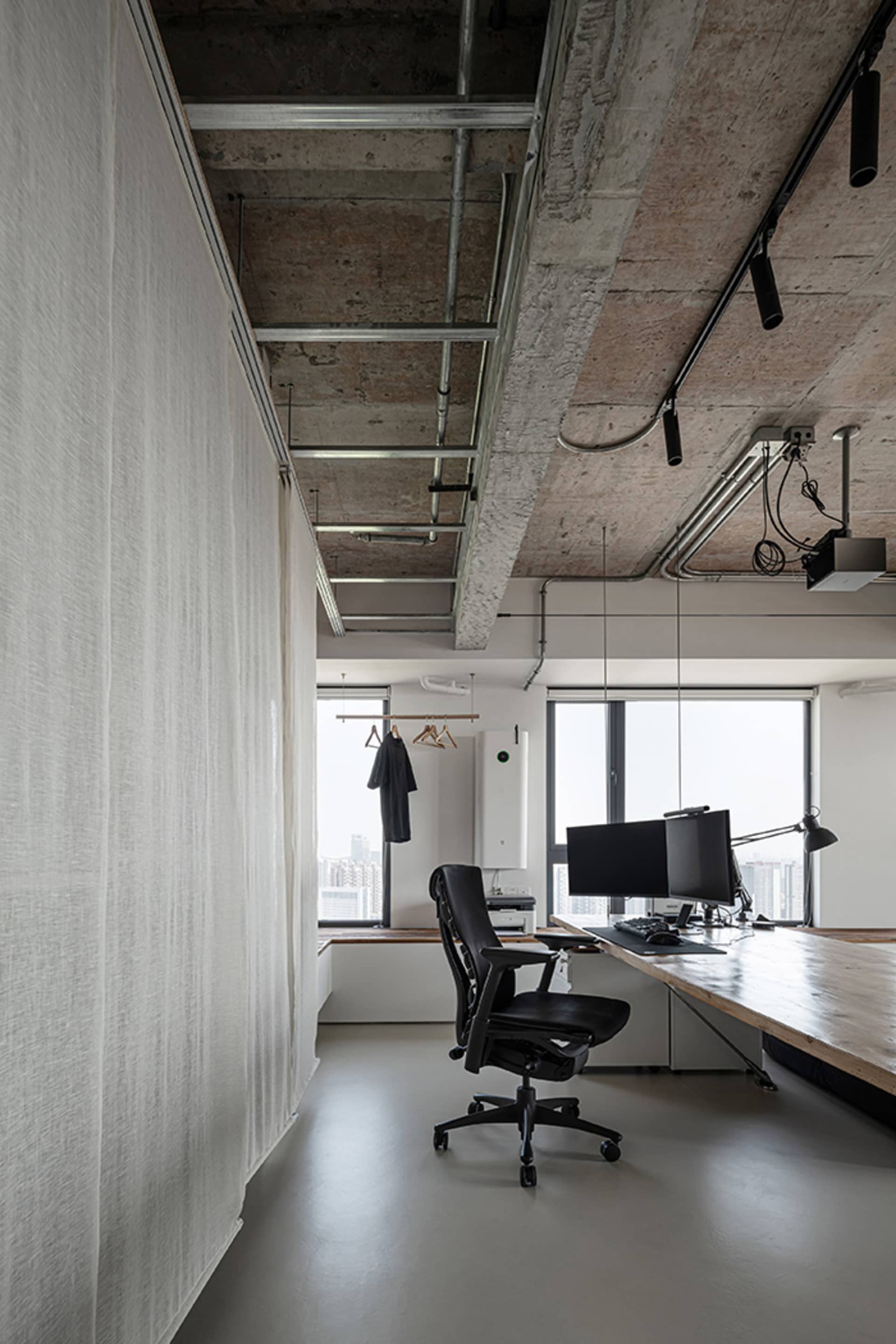 Office space with a desk area, two chairs, a TV screen, and a window view allowing natural light to enter the space