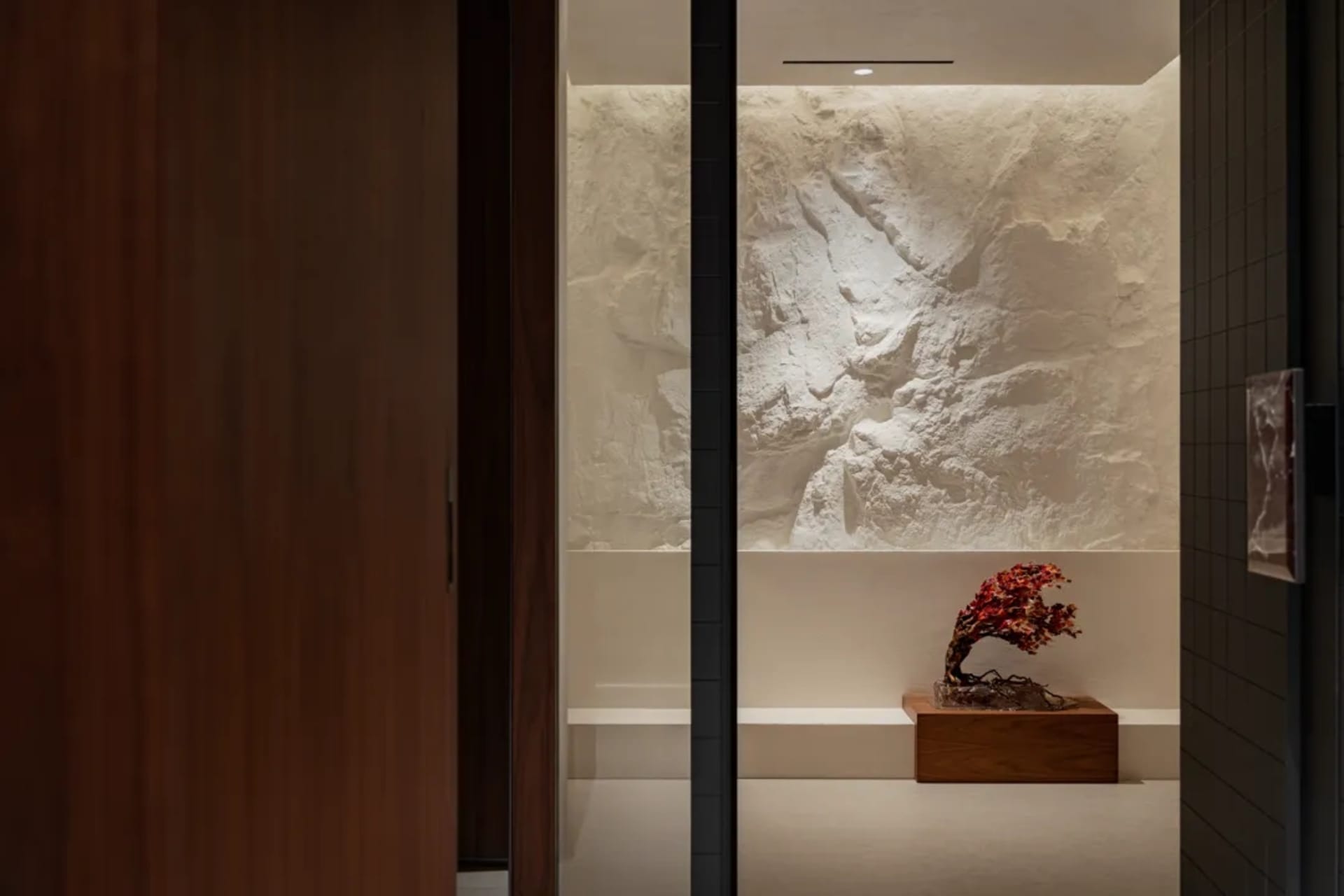 A clean and organized entryway with a wooden doorway, a rock wall, and decorative vases, creating a sense of orderliness