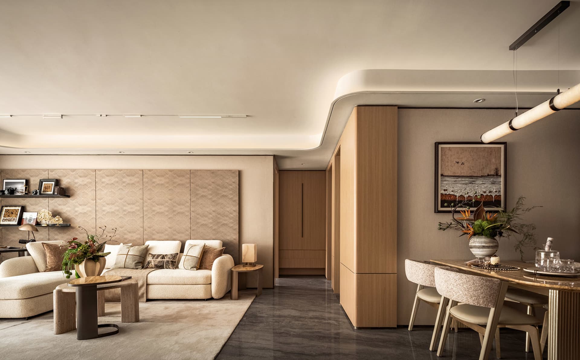 Open modern living space with a large couch, two chairs, a dining table, and a vase, featuring a comfortable and inviting atmosphere