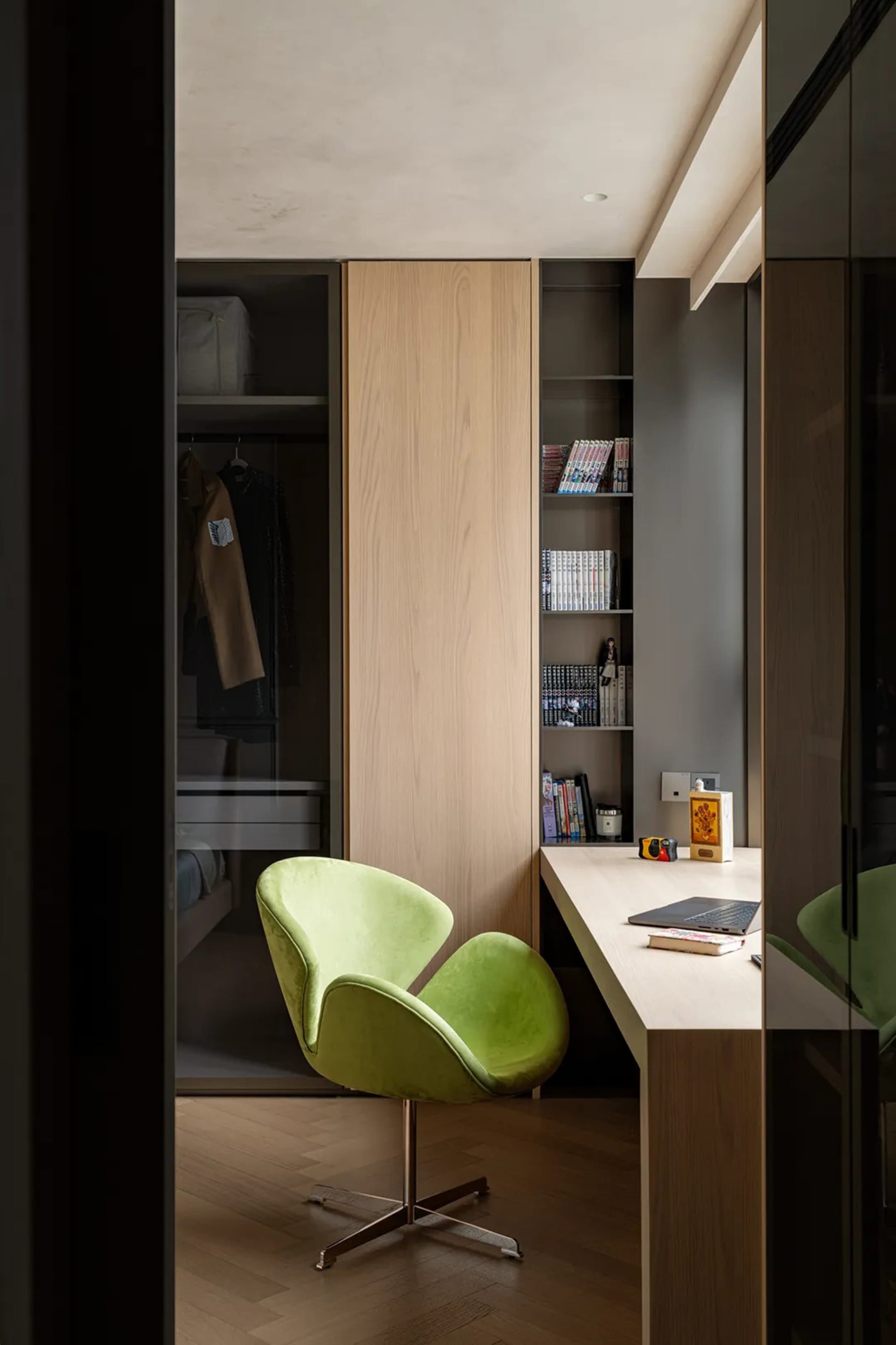 Small office space with a desk, chair, and bookshelf, featuring a laptop and scattered books, with a cozy and functional atmosphere