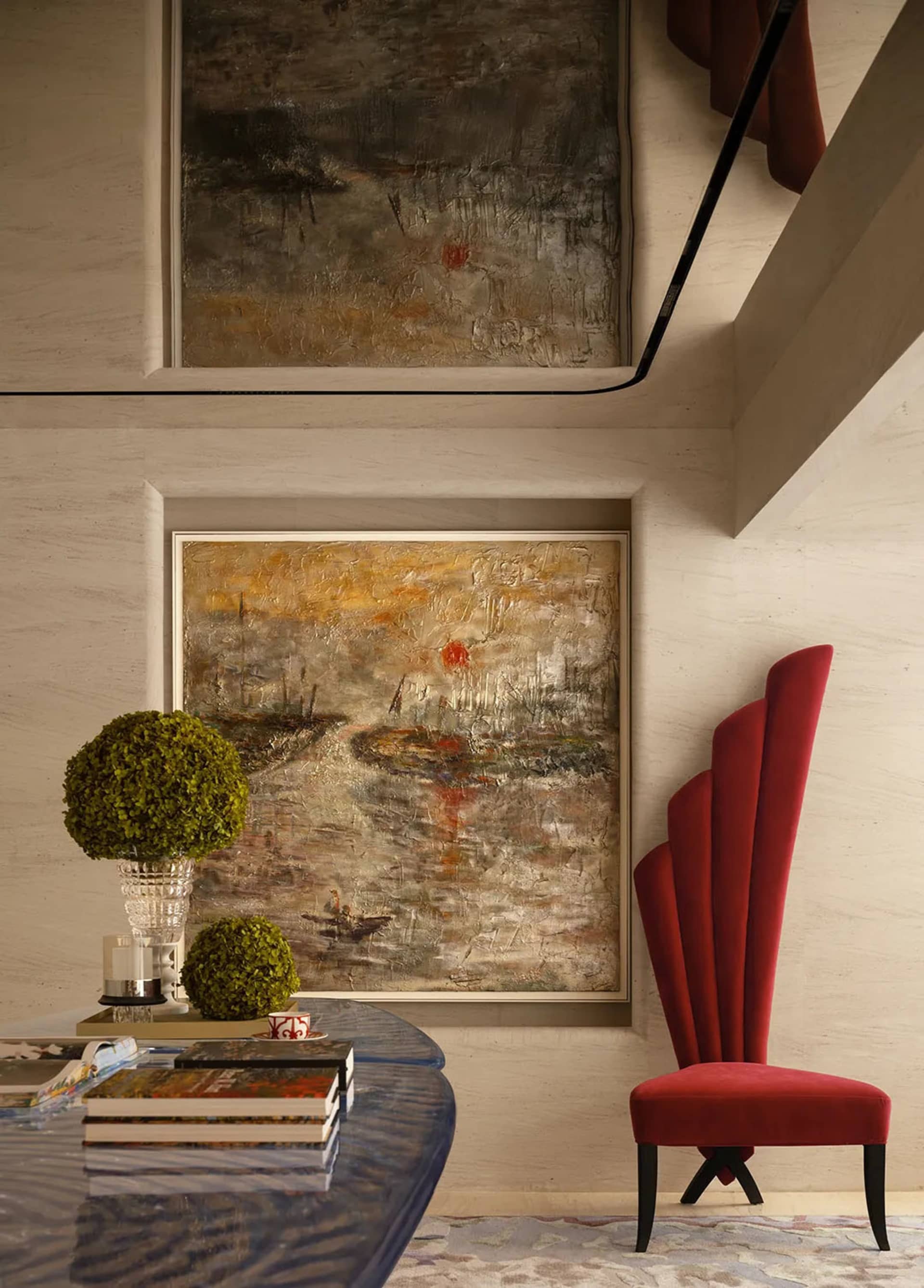 A modern living room with a red chair, vase, and two paintings, set against a white backdrop, creating a cozy atmosphere with warm lighting