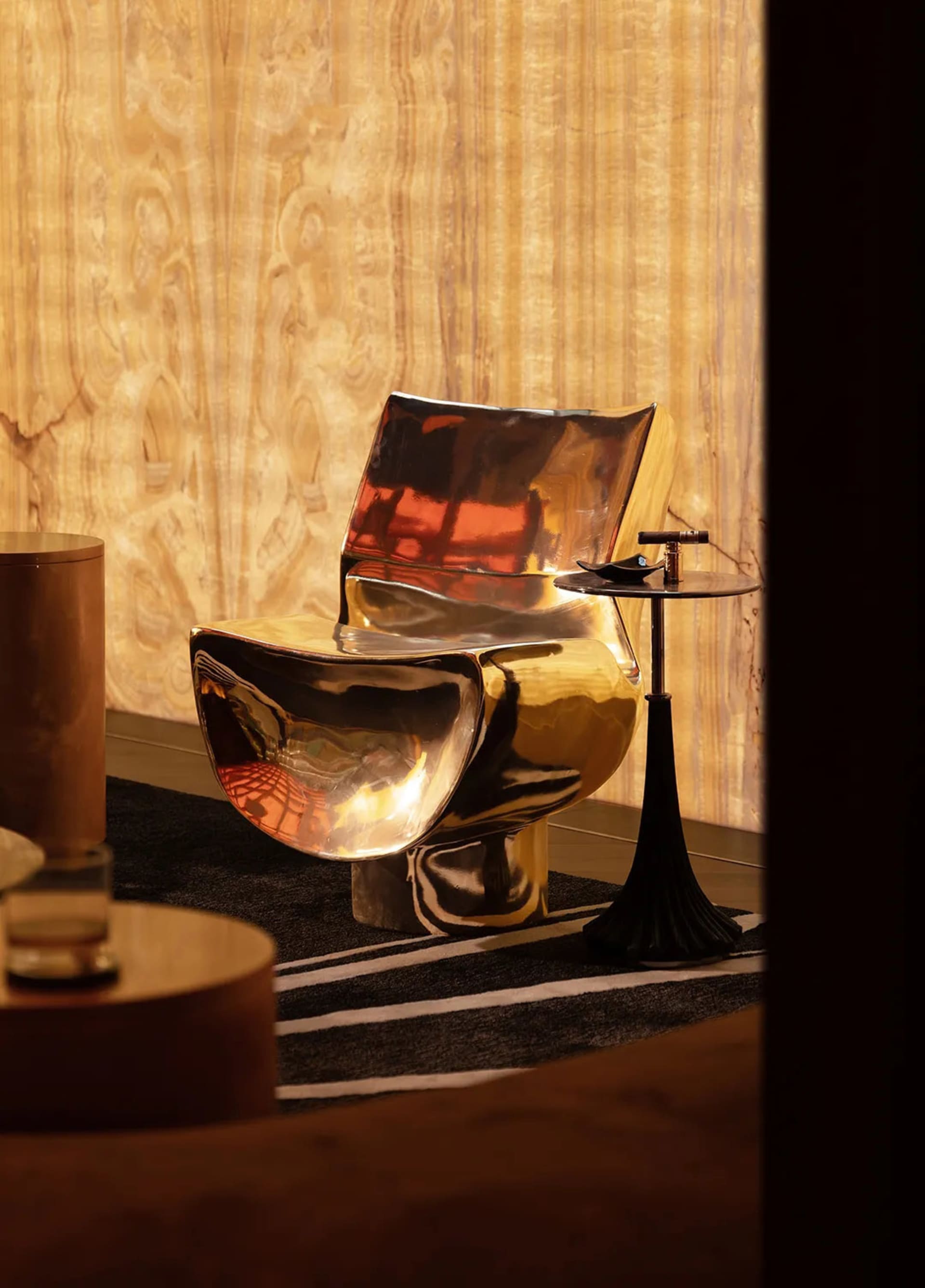 Modern bathroom with a gold toilet, black and white checkered floor, two chairs, and a dining table