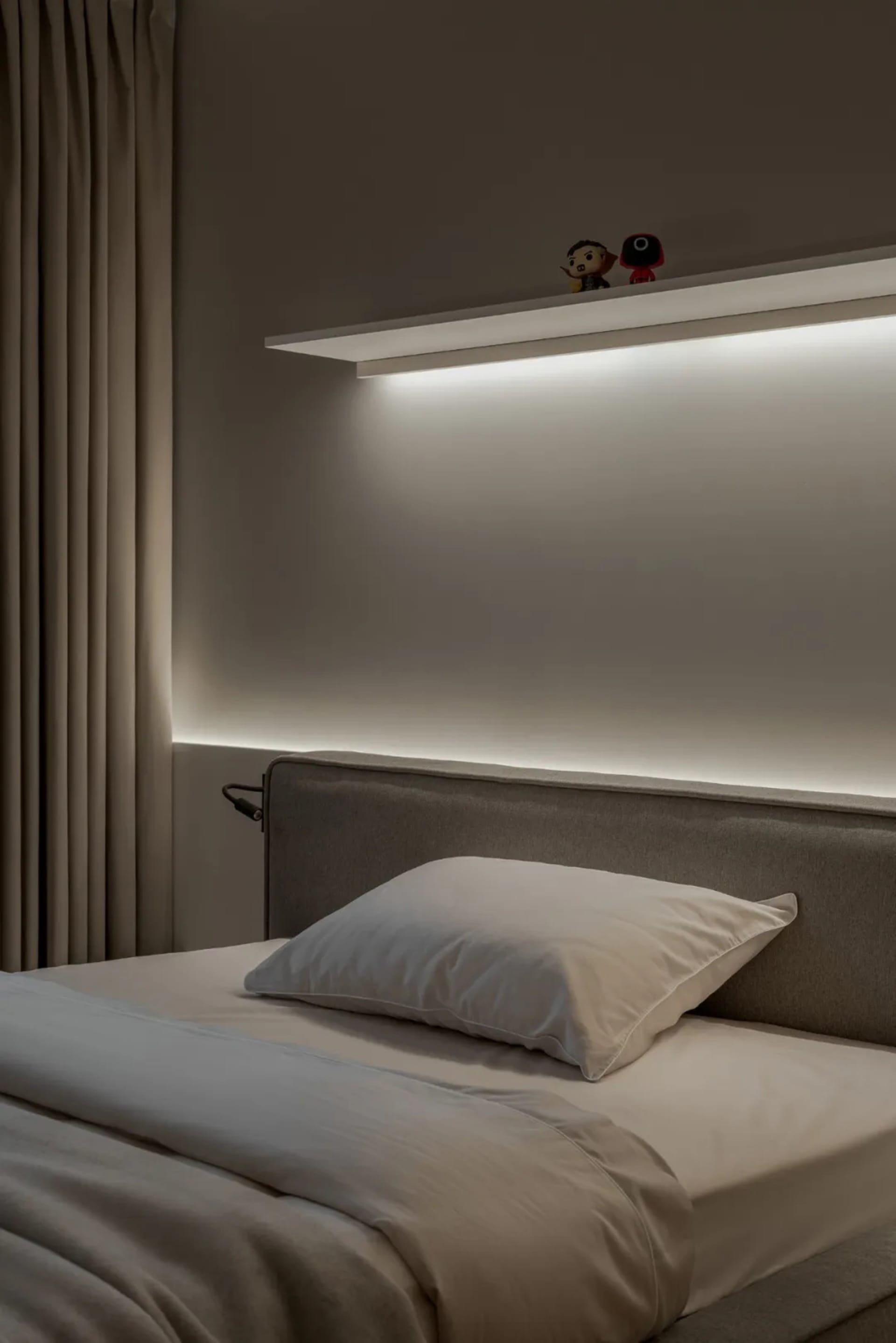 Cozy bedroom with a large white bed, wooden headboard, and two small figurines on the bed