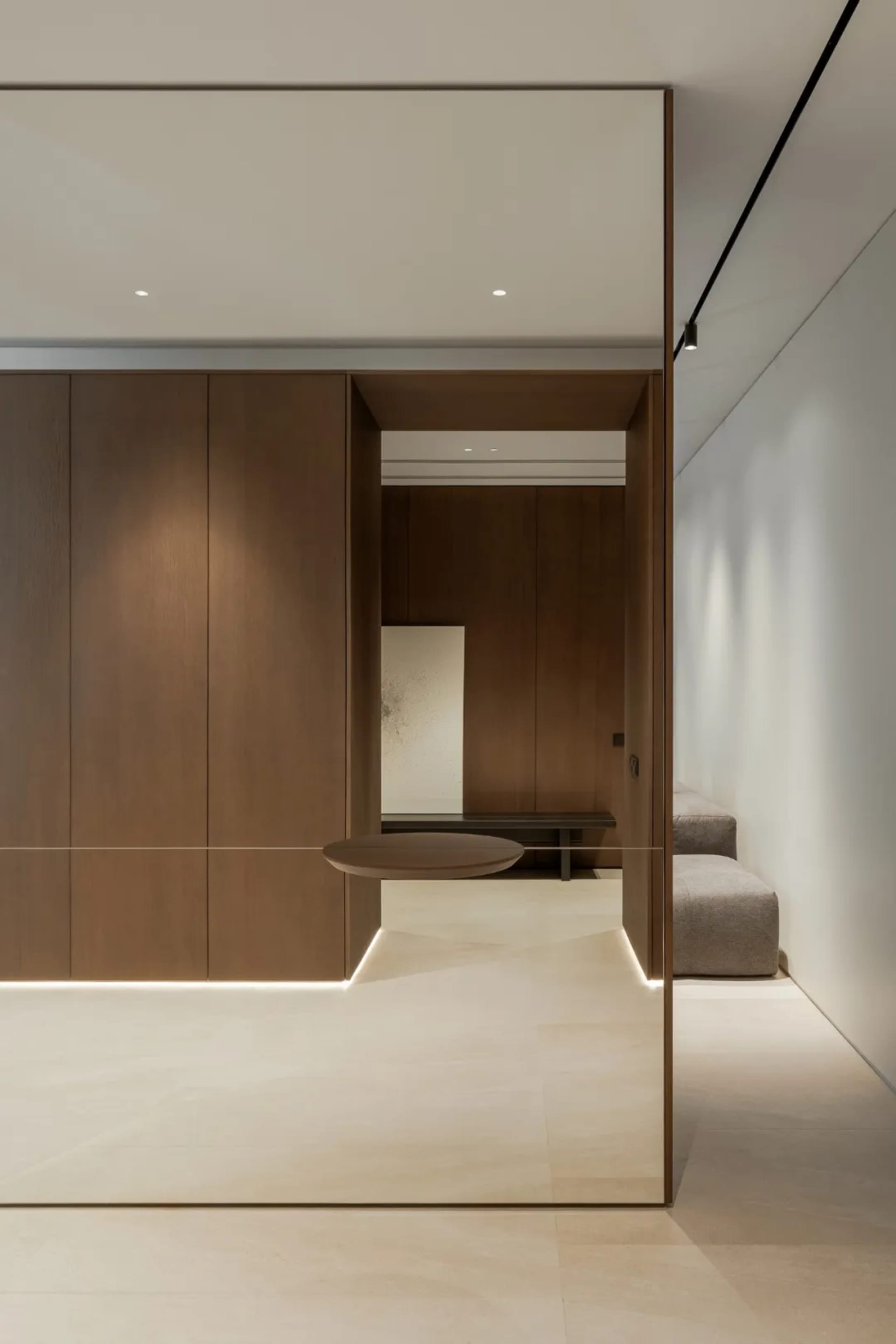 Empty room with wooden walls and floors, featuring two couches and a chair, well-lit with natural or artificial light