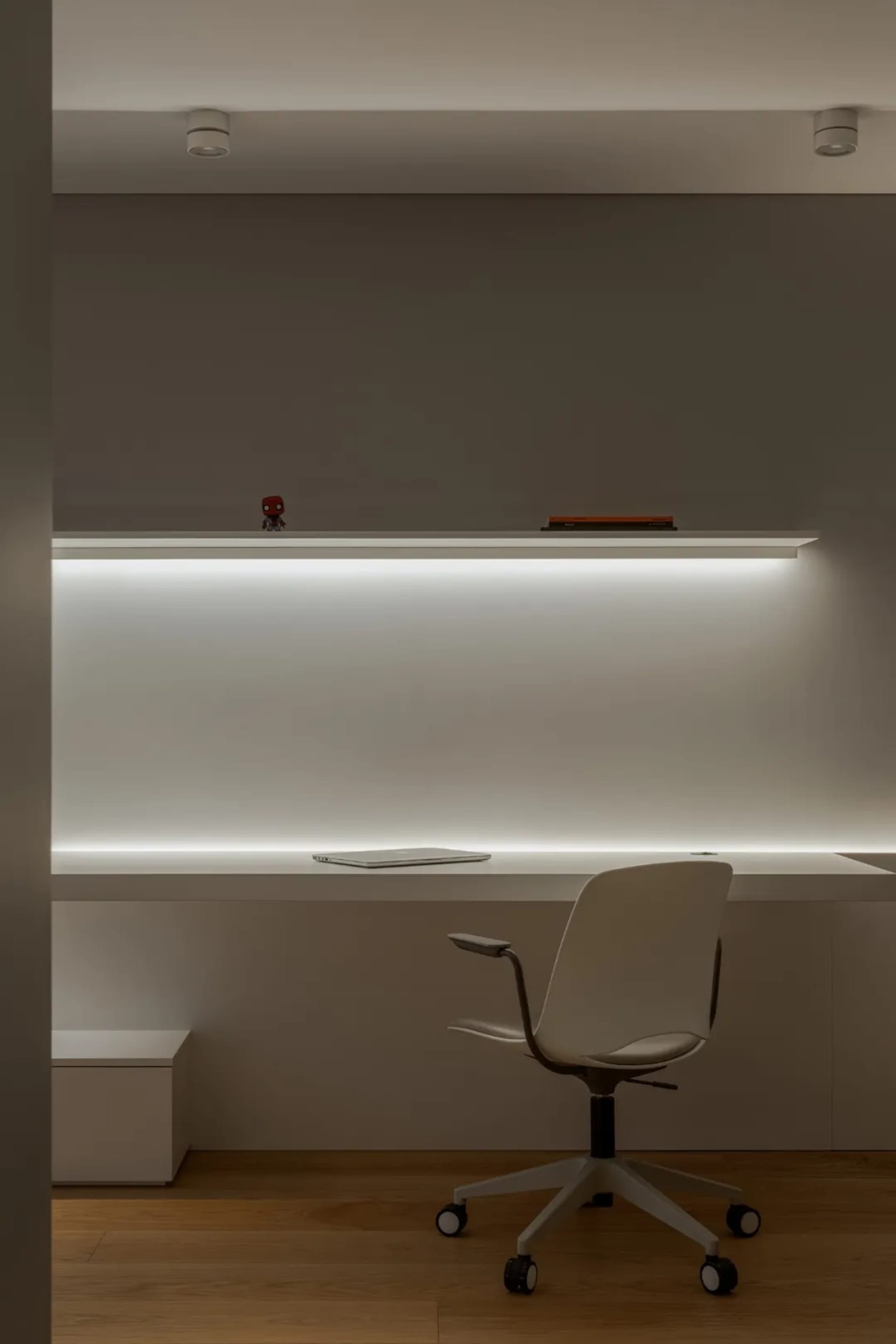 A professional office space with a white desk, two laptops, and three books, with a person partially visible in the background