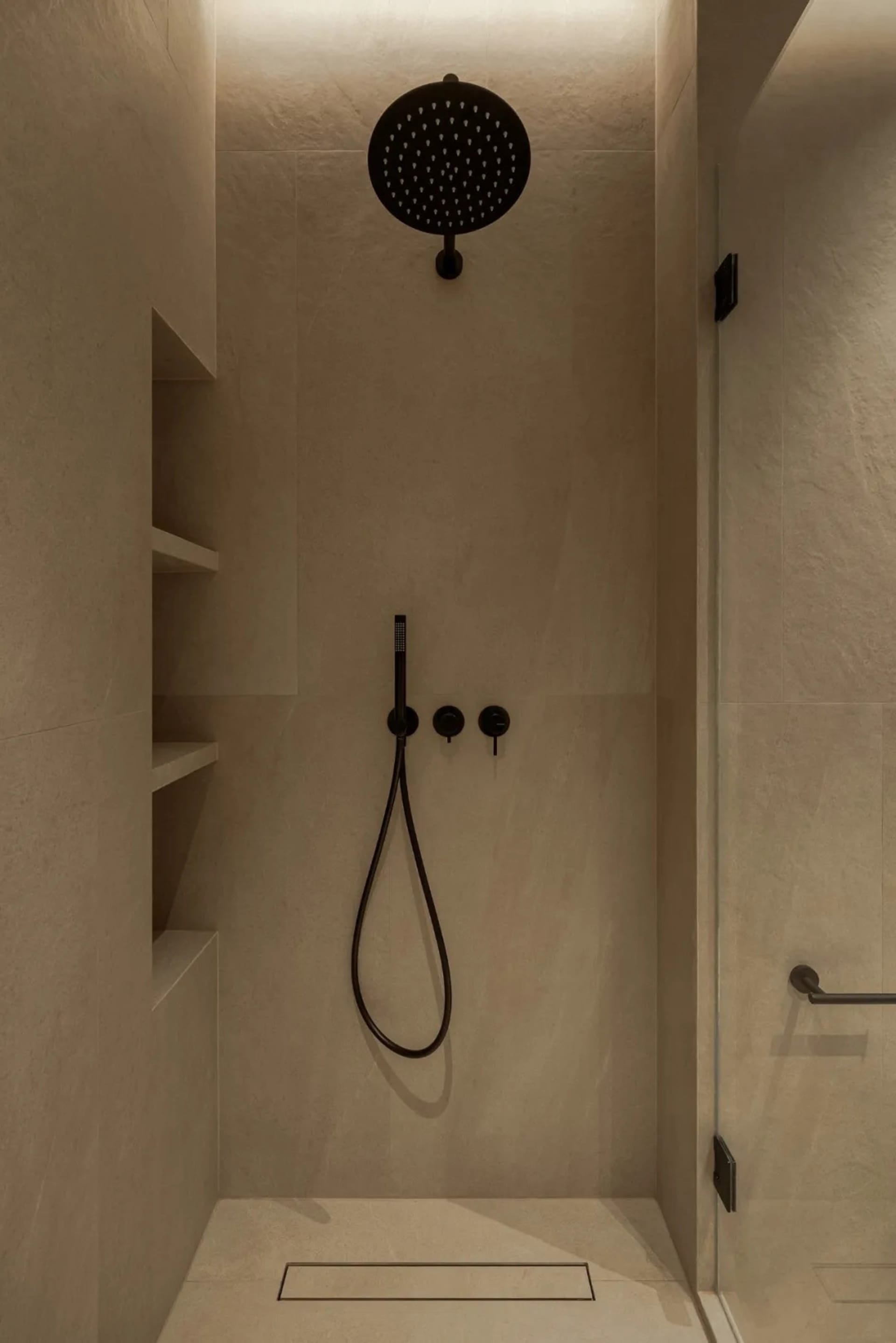 A modern bathroom with a white bathtub and two shower heads, set against a backdrop of tile-walled surfaces