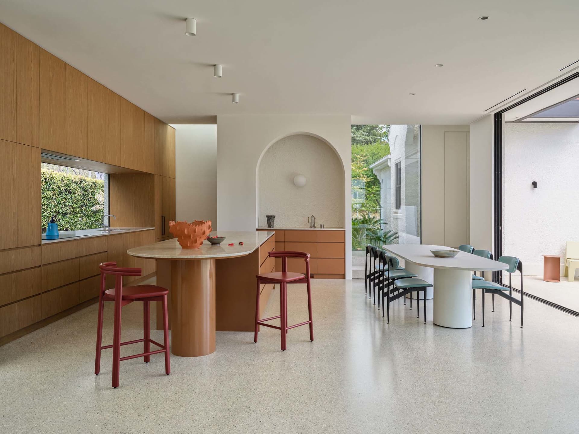 Open kitchen and dining area with a large island, wooden cabinets, and natural light