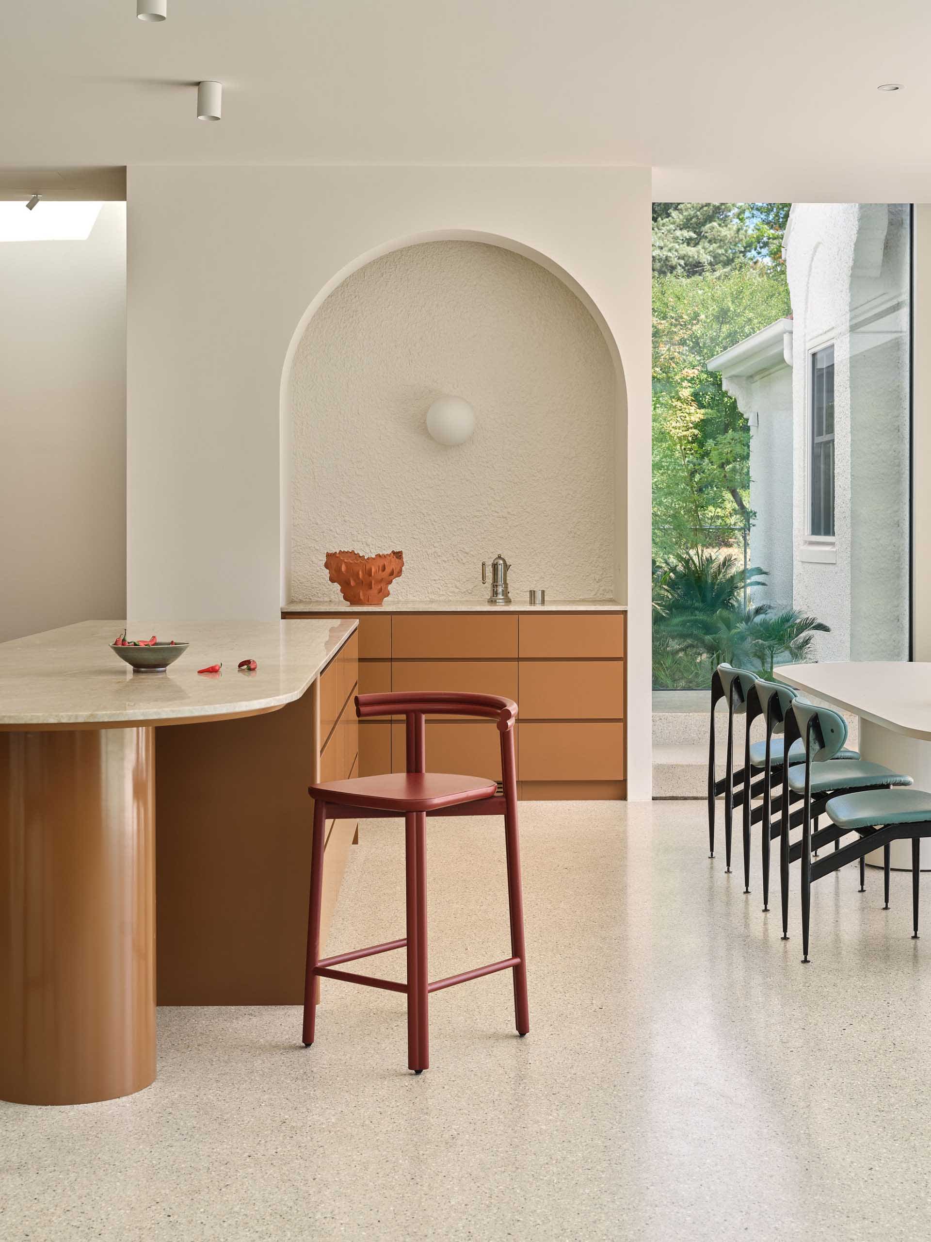A cozy kitchen dining space with a white table and red and black chairs, a kitchen counter with a sink and a bowl, and an inviting atmosphere