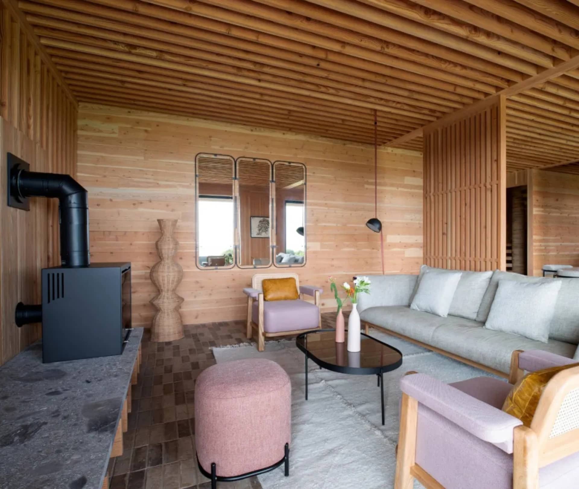 Warm and inviting living area with a large couch, fireplace, wooden floors, and a dining table in the background