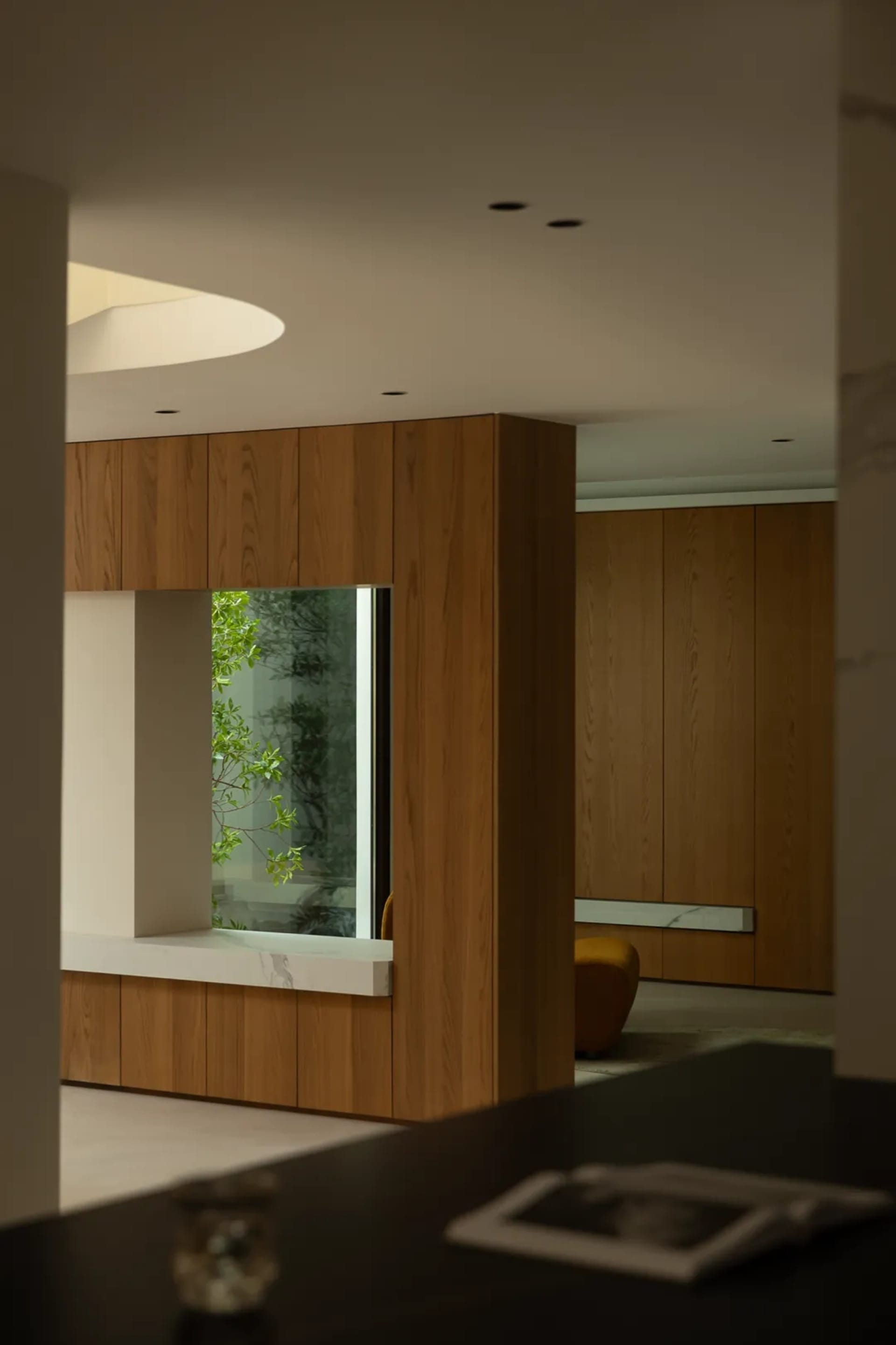 Warm and inviting living space with wooden walls and floors, featuring a couch and chair, and large windows on either side of the room