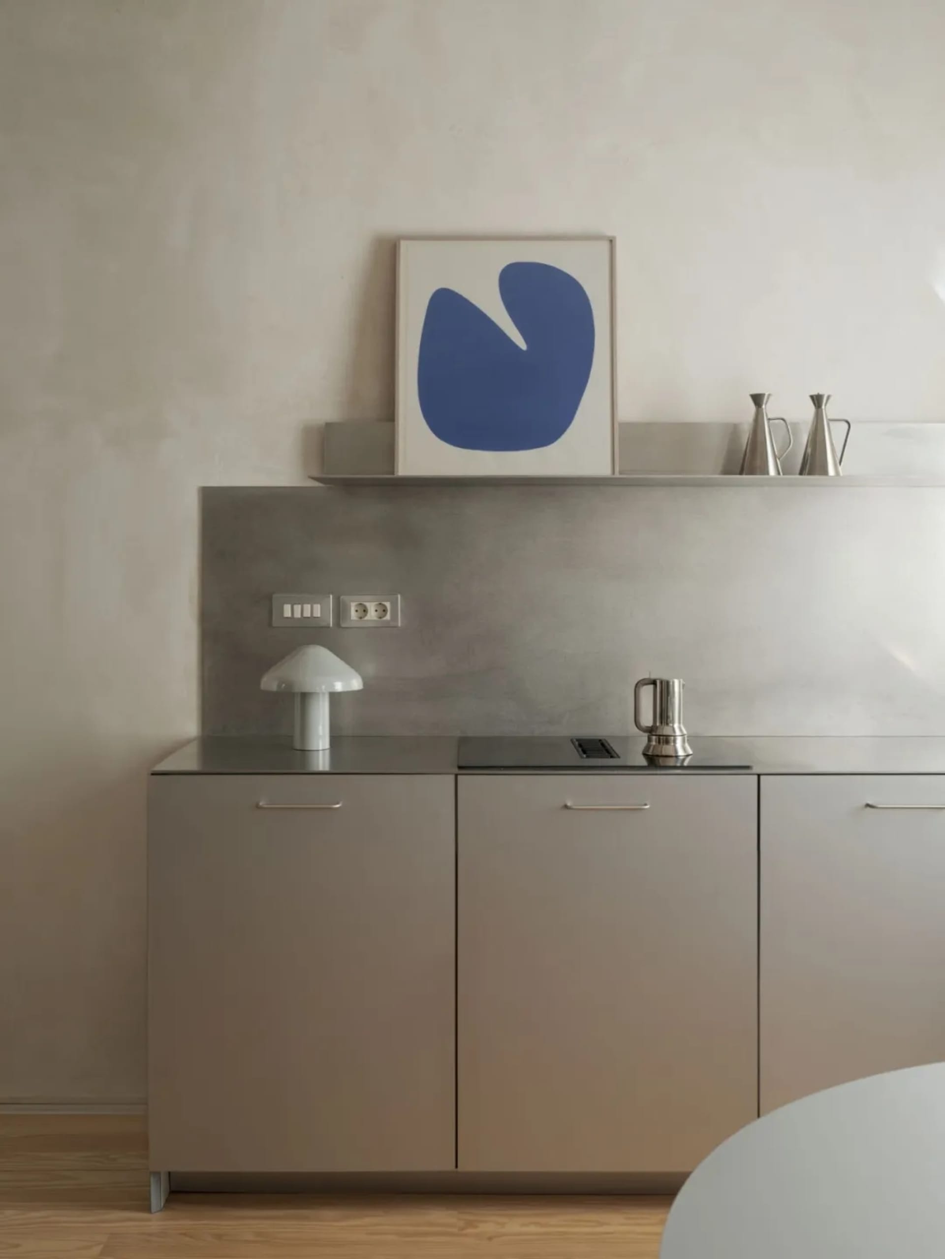 A clean and organized kitchen with a sink, refrigerator, and countertop, featuring two bottles and three cups arranged in a neat and tidy space