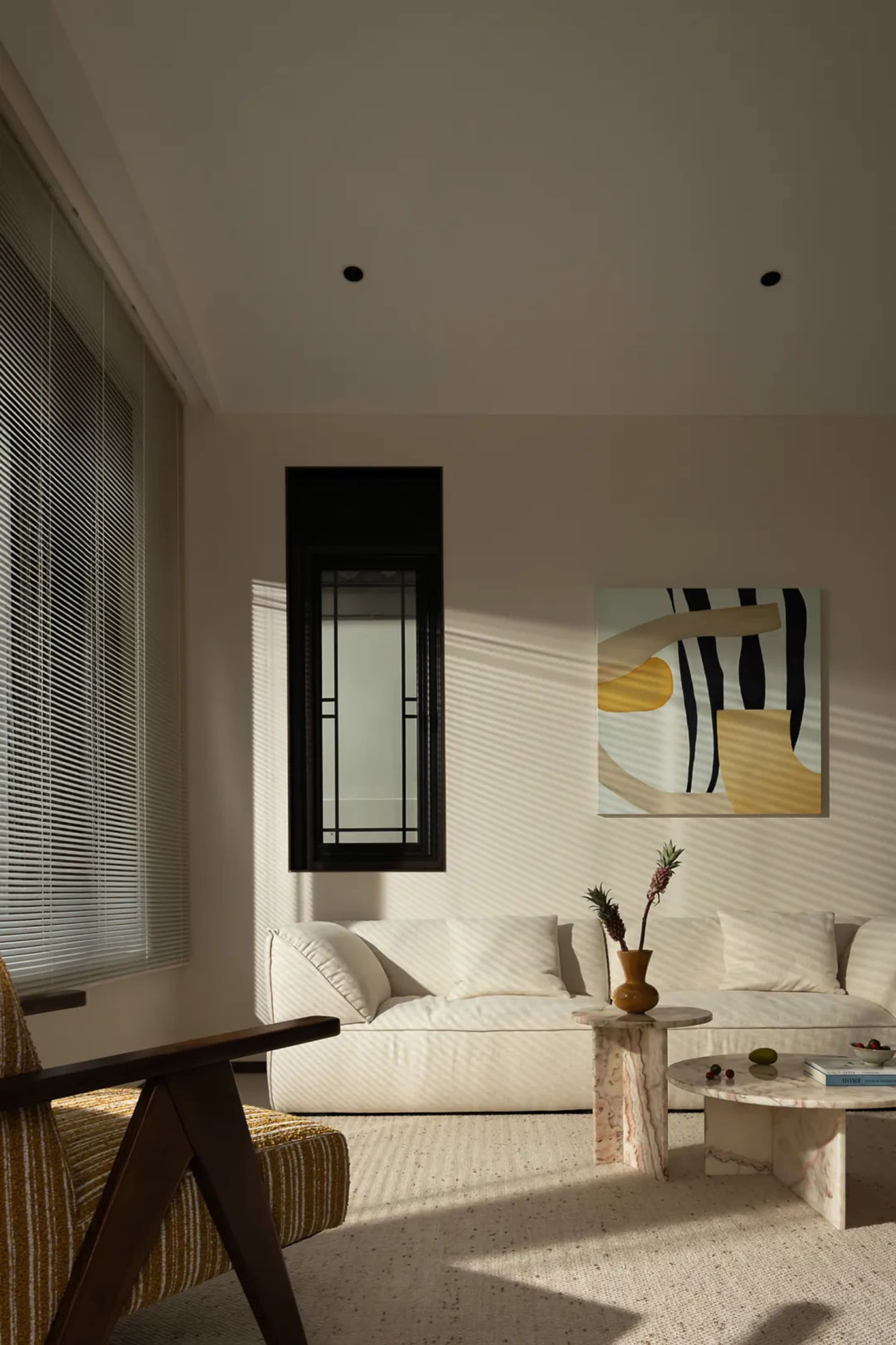 Bright and inviting living area with a white couch, chair, and dining table, featuring natural light and a potted plant