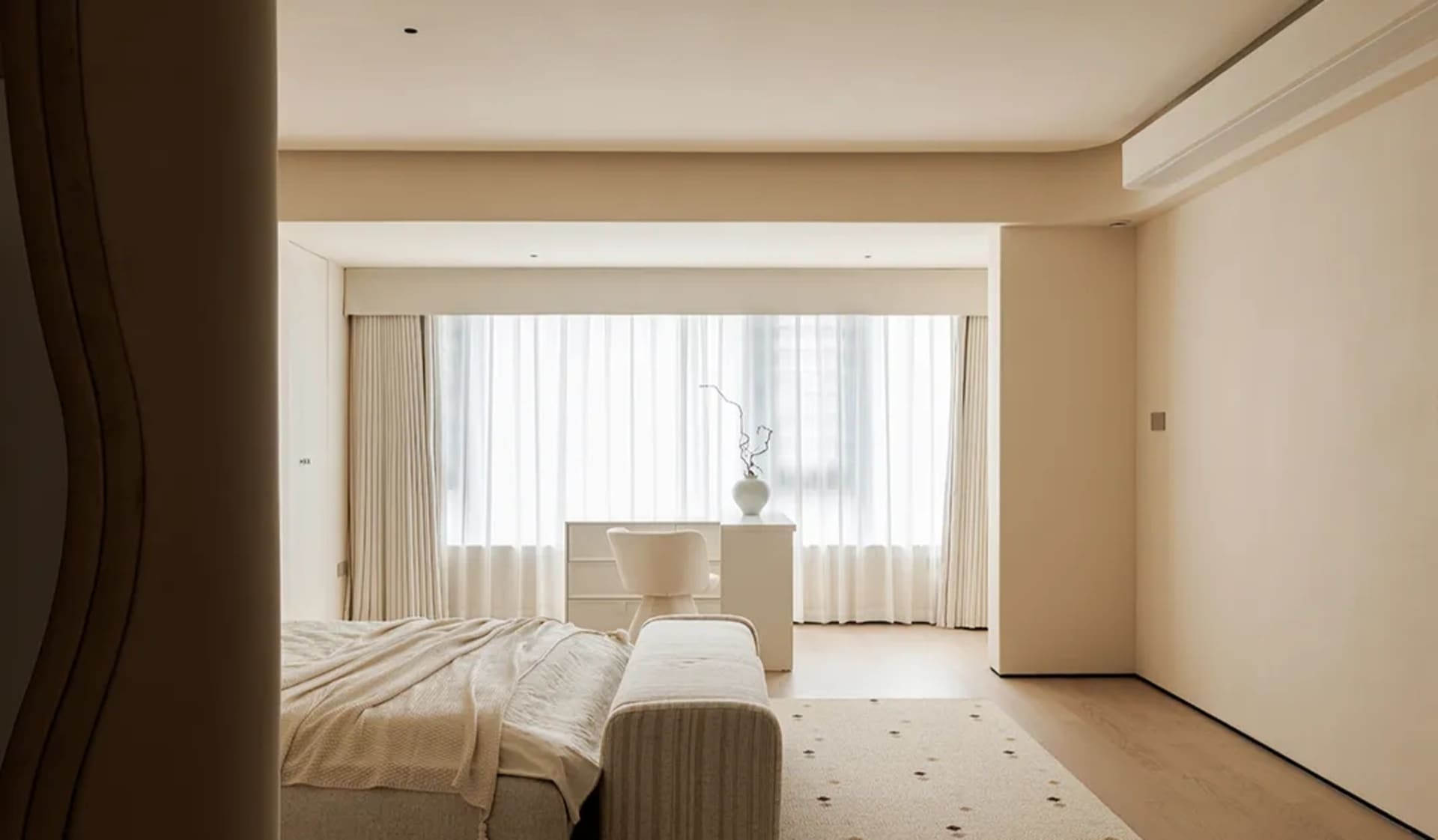 Modern bedroom with a large bed, chair, couch, and potted plants, giving off a clean and modern vibe