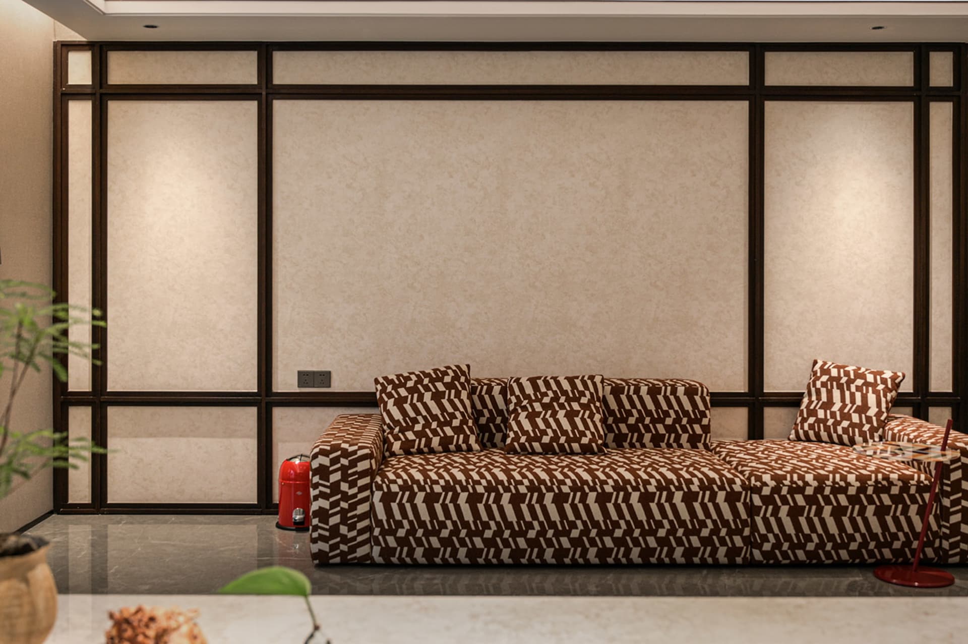 Cozy living room with a brown couch, zebra print pillows, and a potted plant on a hardwood floor, with a fire hydrant in the corner