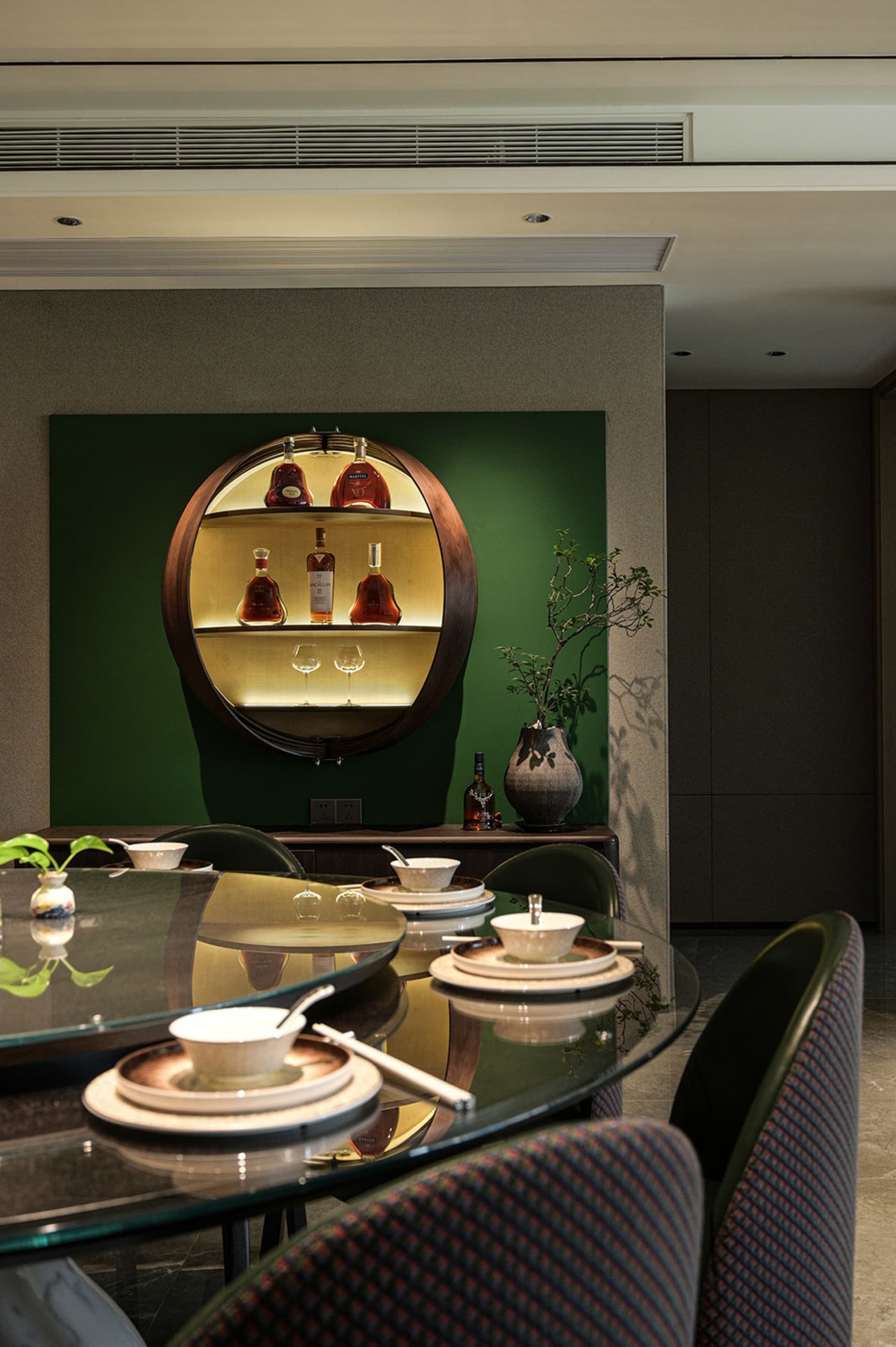 A dining area with a wooden table and chairs, surrounded by wine bottles on a shelf, in a restaurant with an elegant and sophisticated ambiance