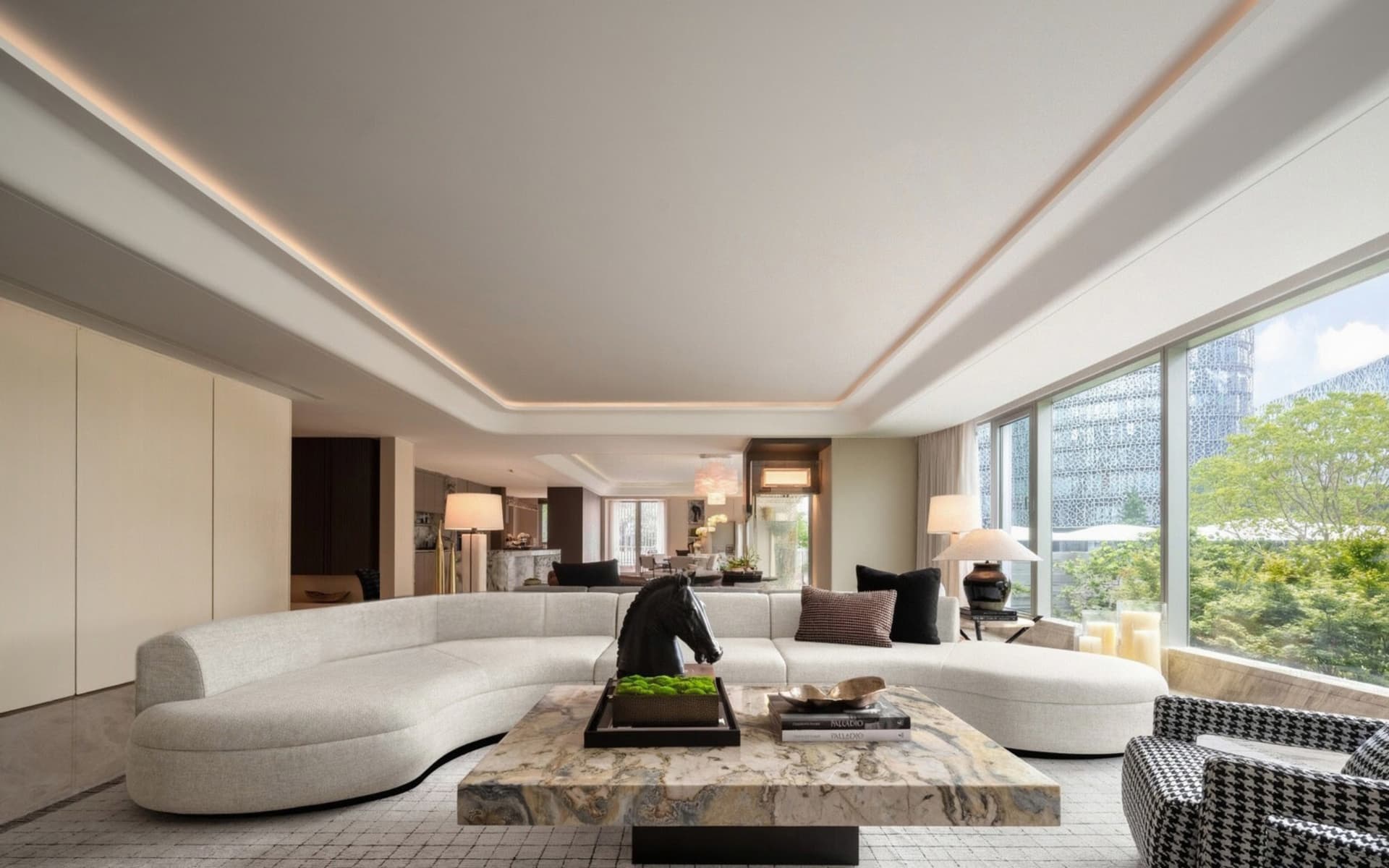 Open living area with a large couch, smaller couch, chairs, dining table, potted plants, and decorative vases in a clean and minimalist space with neutral tones