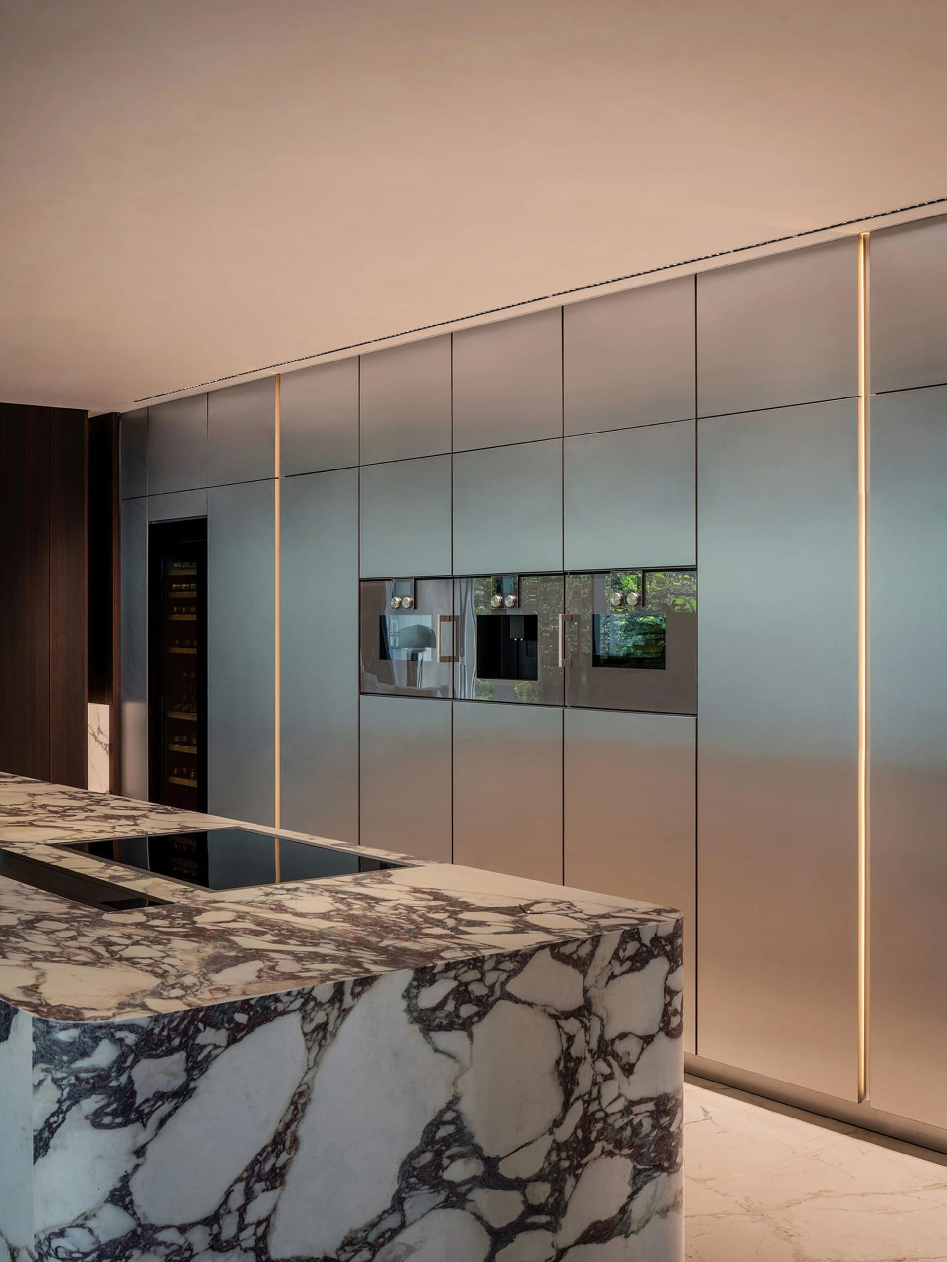Well-lit kitchen with marble countertops, stainless steel appliances, and bottles on the countertop