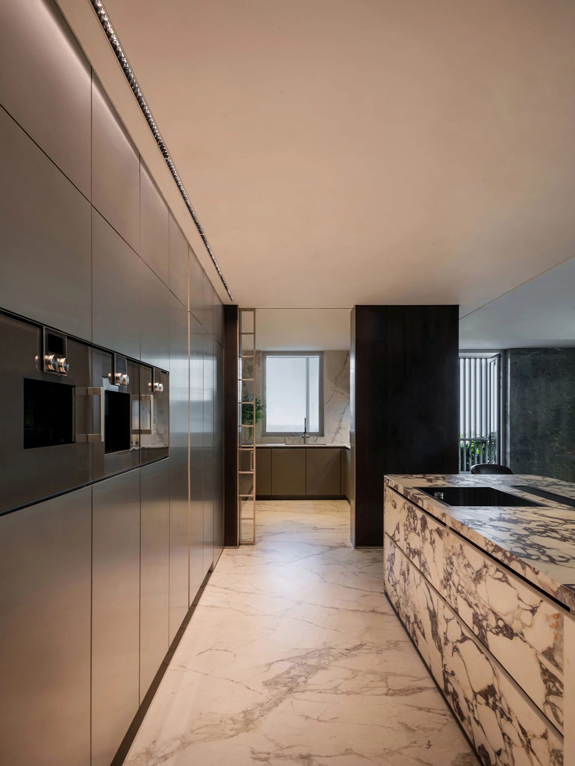 Modern kitchen and dining space with white marble countertops and flooring, featuring two sinks, a refrigerator, and a potted plant