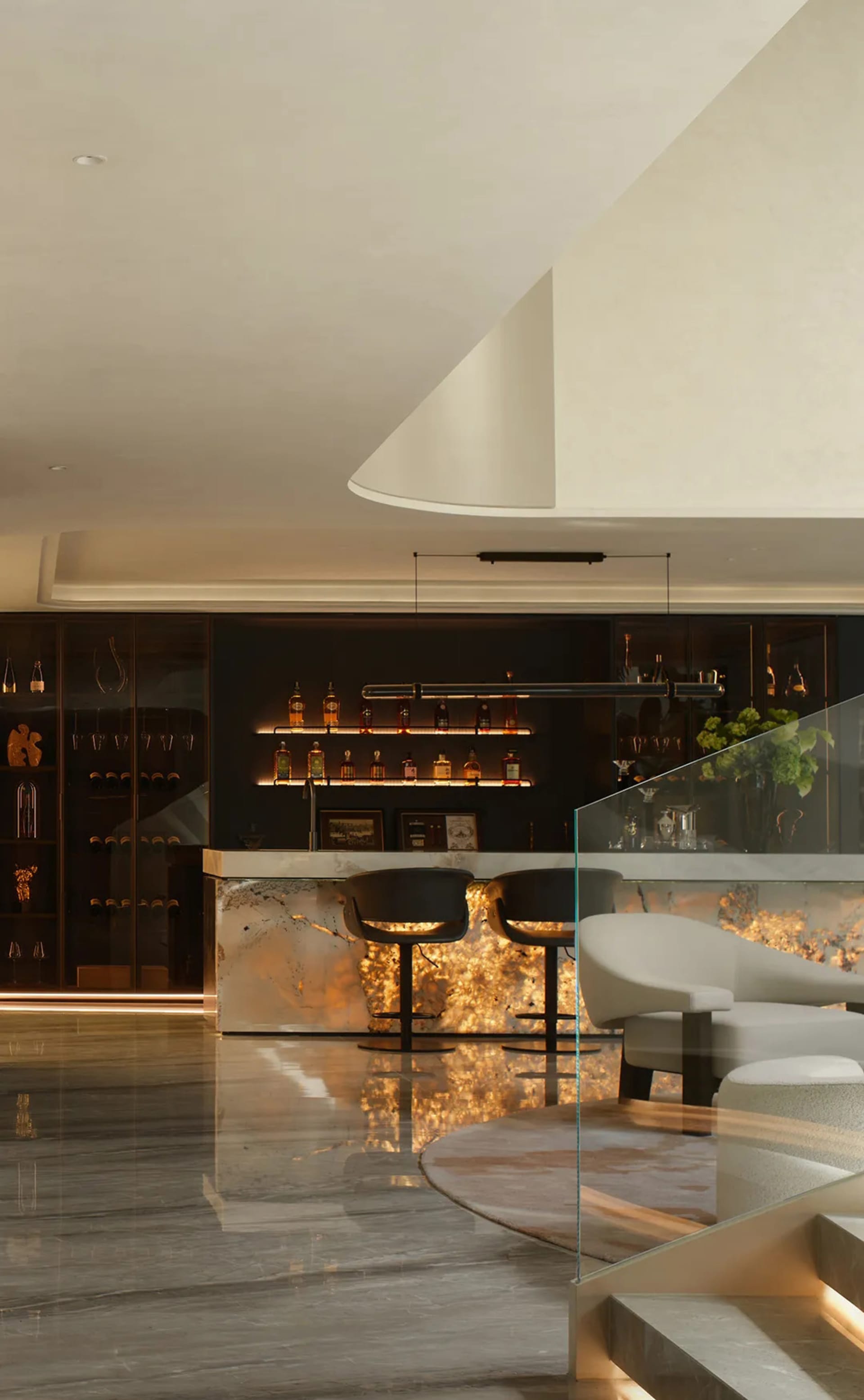 A modern bar area with a well-stocked counter, wine glasses, and comfortable seating for patrons