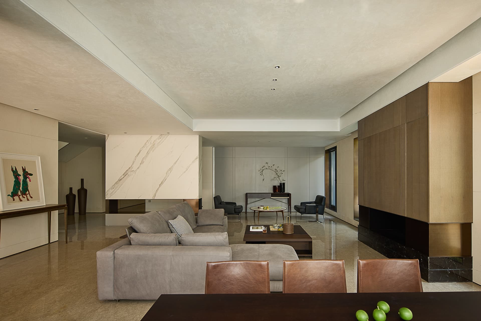 Open living space with a large couch, two chairs, a dining table, and potted plants, featuring modern design with neutral tones and clean lines