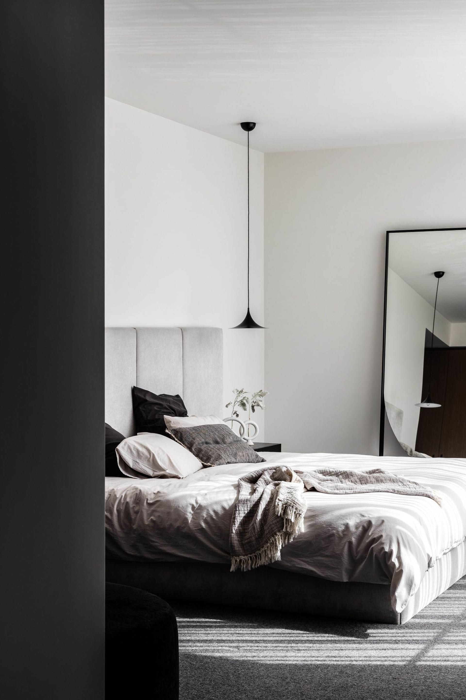 Empty bedroom with a white bed, two pillows, and natural light from windows