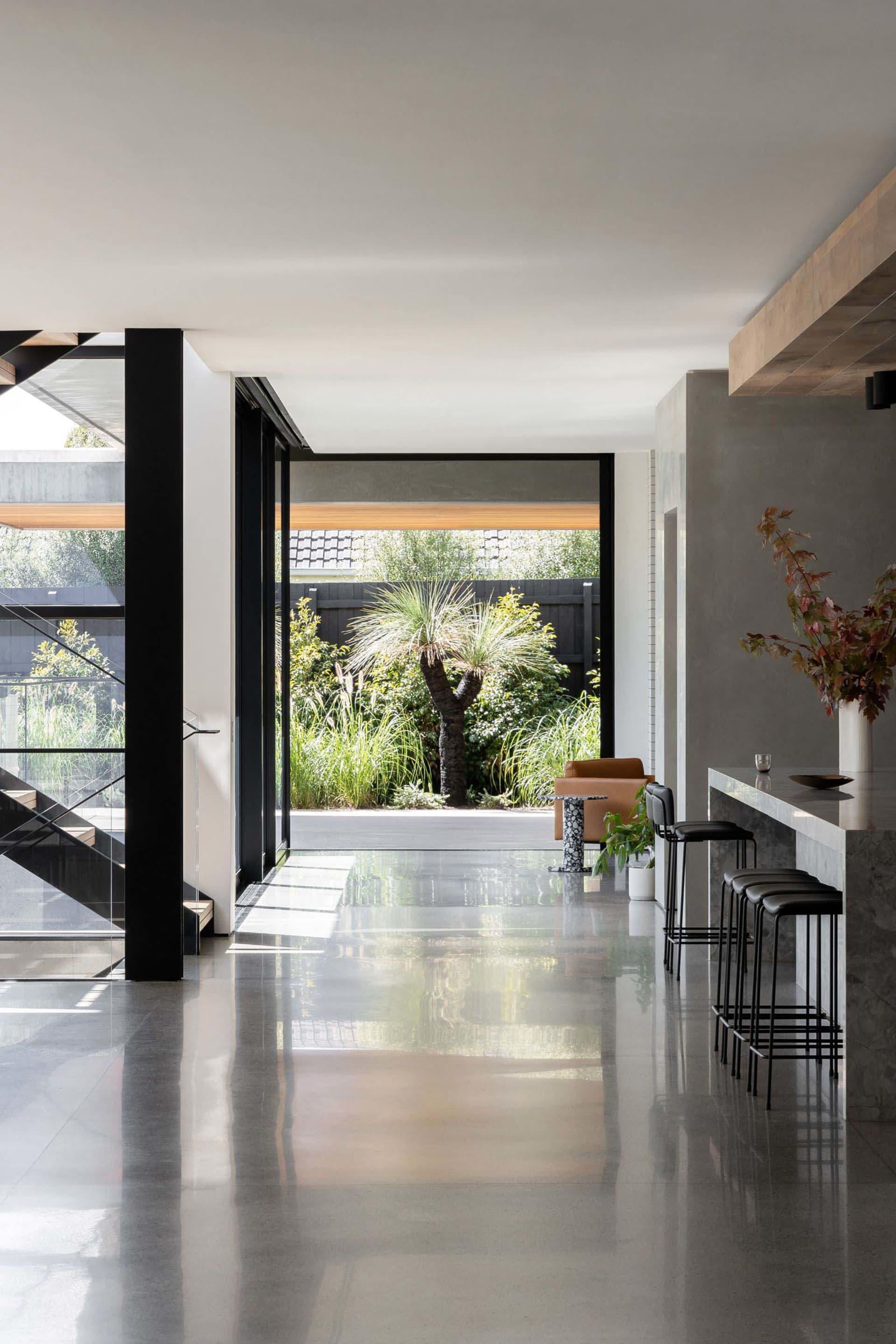 Modern open plan living area with white walls and floors, featuring a kitchen, dining room, and living room with two chairs and a dining table