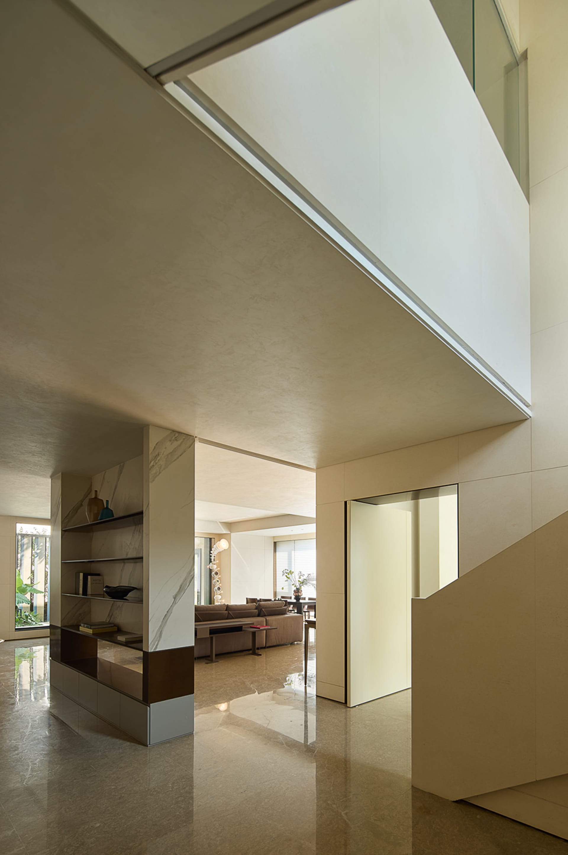 Open living space with a couch near a window, chairs, a dining table, vases, and a potted plant, showcasing a bright and inviting atmosphere with contemporary design and minimalistic decoration