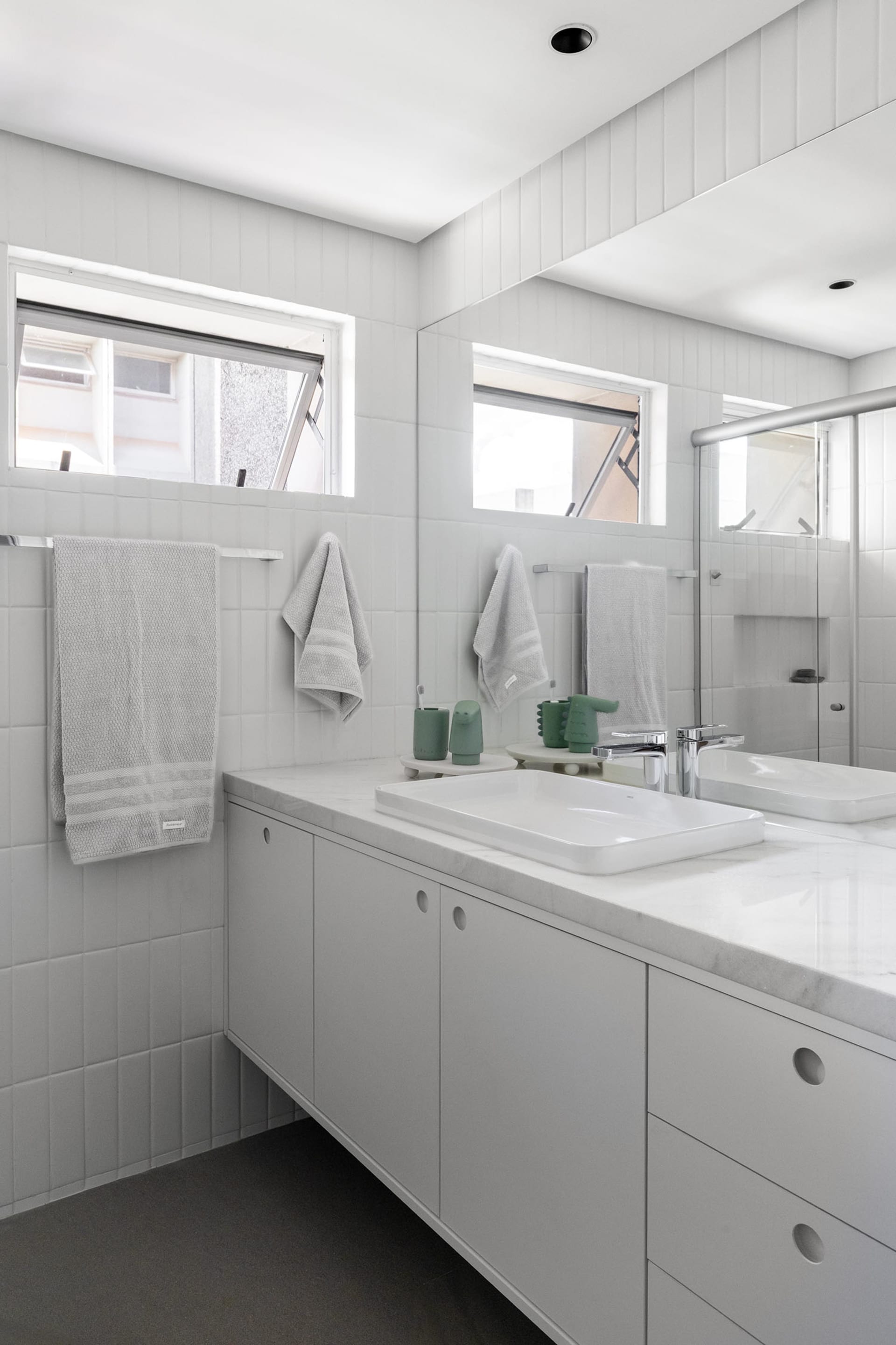 A minimalist bathroom with a white sink, mirror, and towel rack, featuring two towels and a clean design