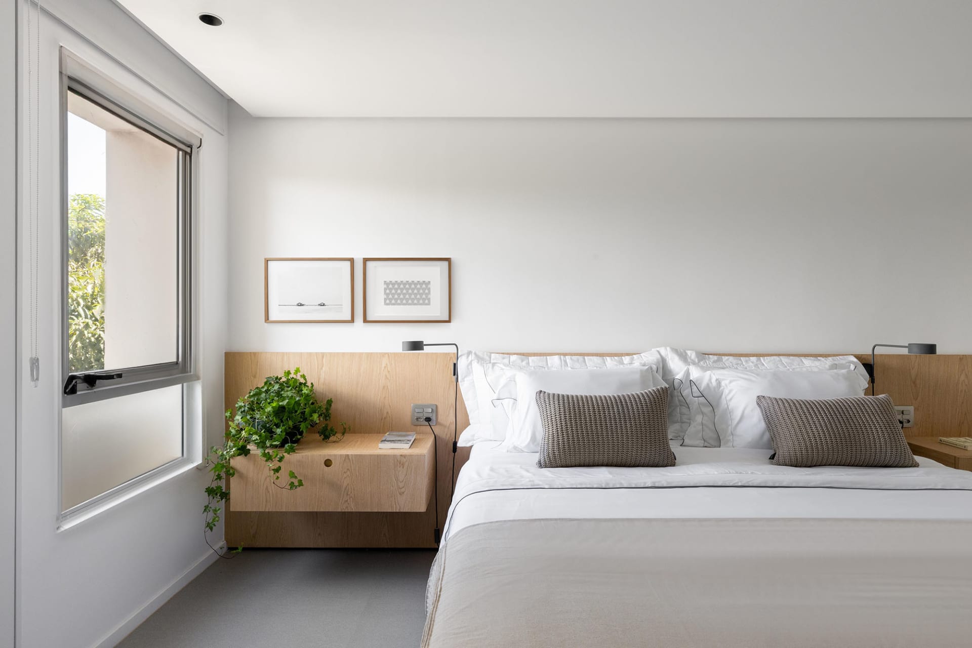 A cozy bedroom with two twin beds, potted plants, and a book, creating a relaxing atmosphere