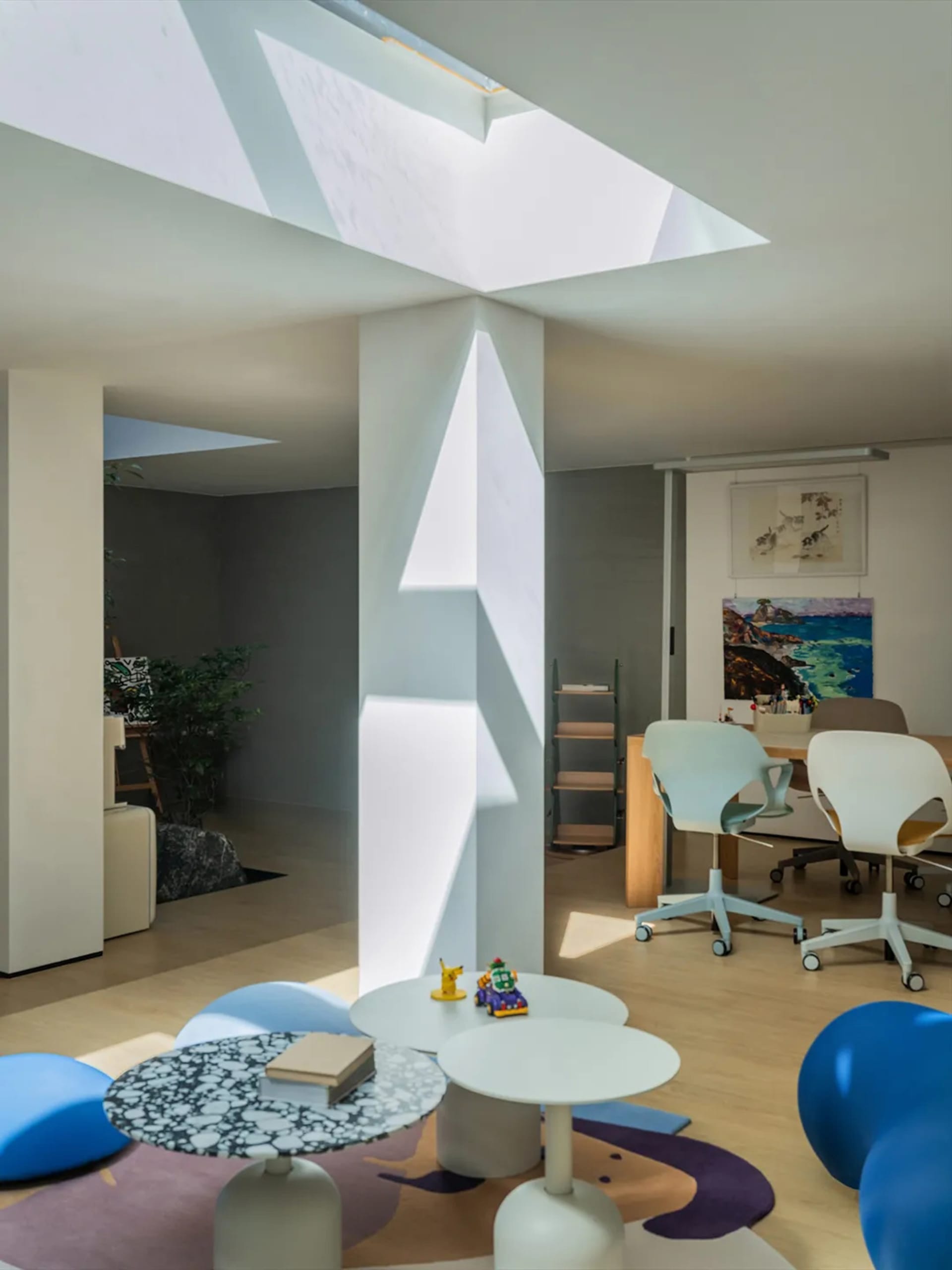 Open living area with a unique white wall design, furniture, books, and natural light