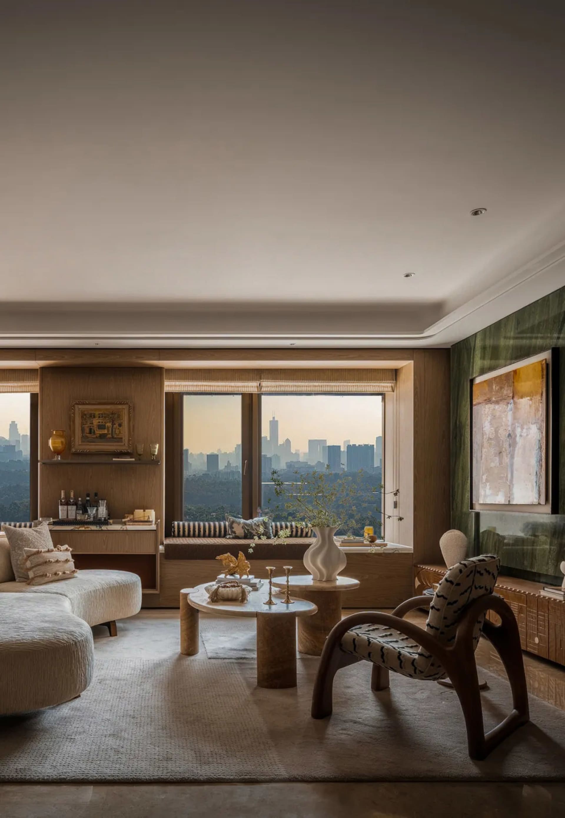 Modern living room with hardwood floors, a couch, chairs, tables, and a large window overlooking the city skyline