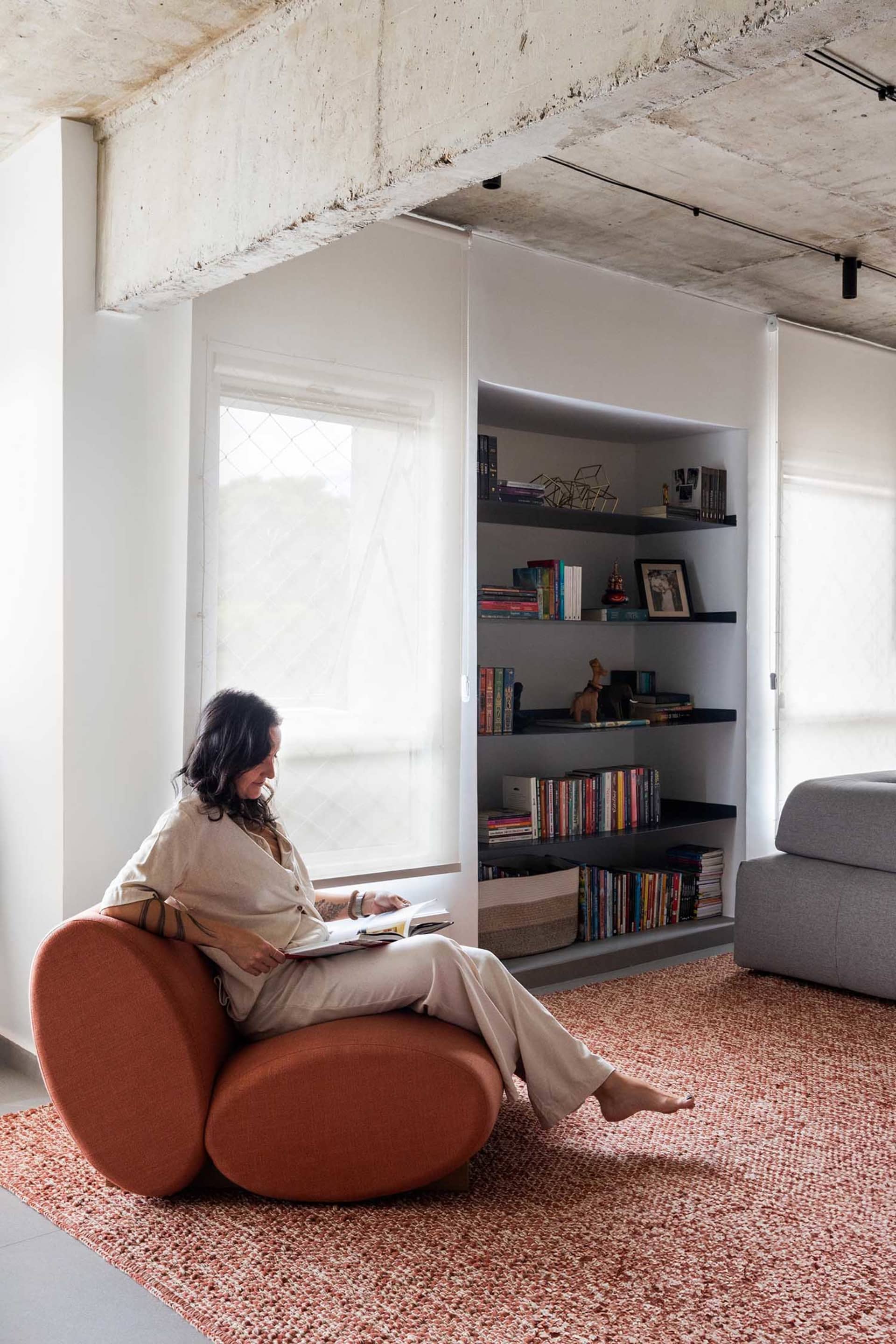 A woman reads a book in a cozy living area with a couch, bookshelf, and vases, creating a warm and inviting atmosphere