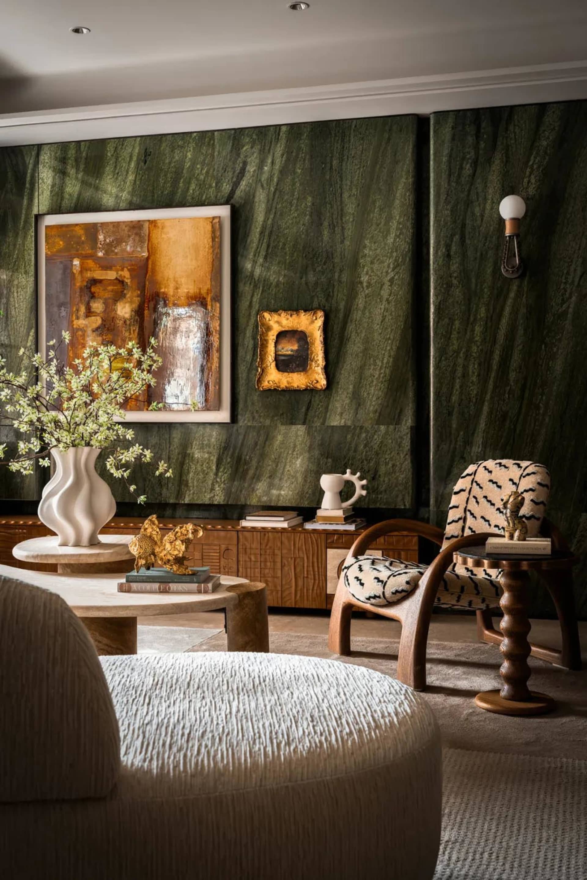 Elegant living area with a large marble wall, two chairs, a vase, and books, conveying a sense of comfort and luxury