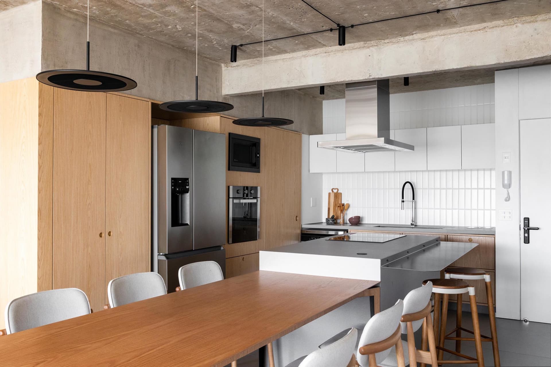 Open kitchen area with wooden floors, white walls, and various appliances, including a refrigerator, oven, and sink, with multiple bottles placed around the space, creating a clean and organized atmosphere