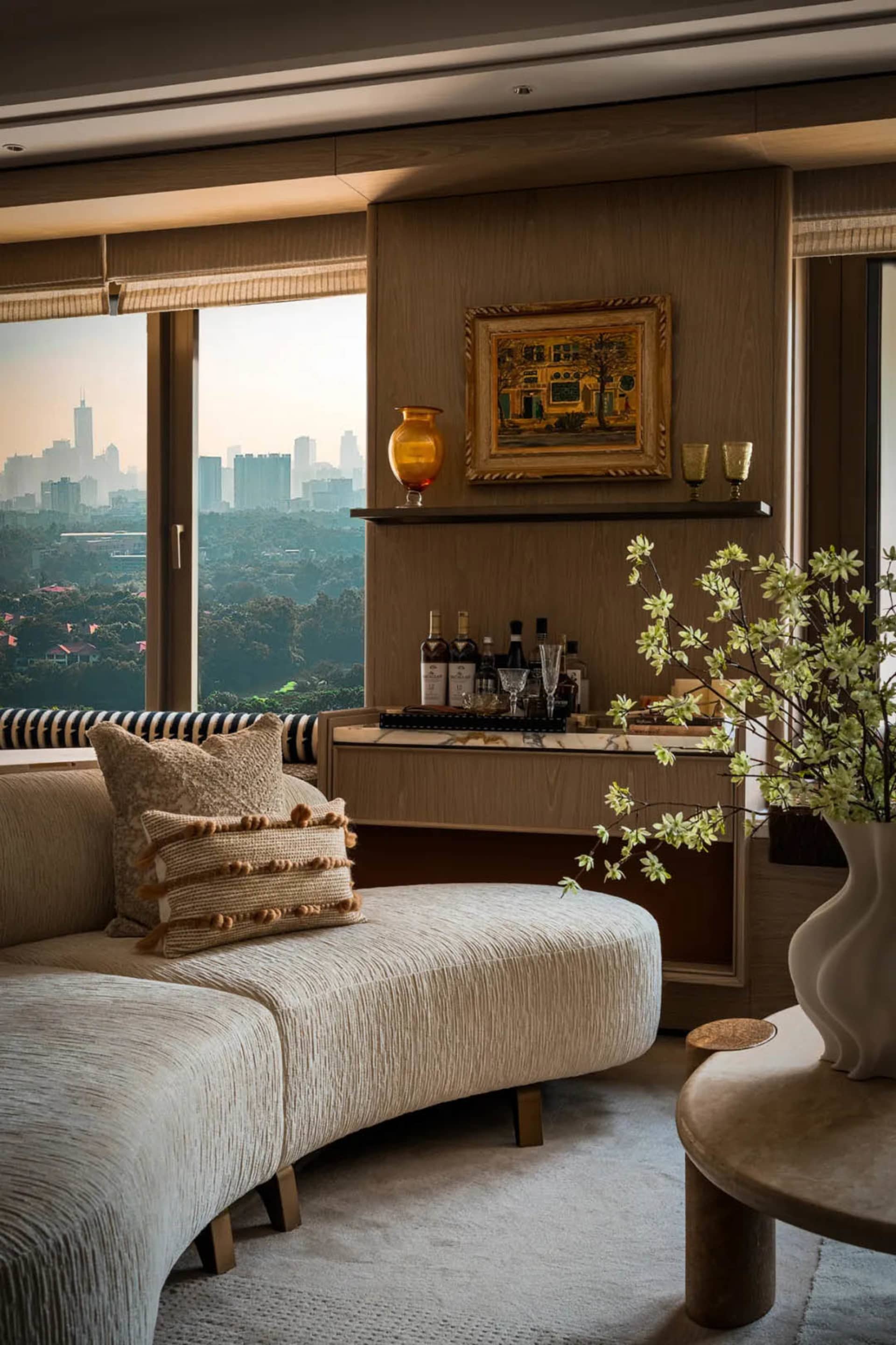 A cozy living room with two couches, a chair, dining table, and decorative items, featuring a large window for natural light and artistic vases, with a warm and inviting atmosphere