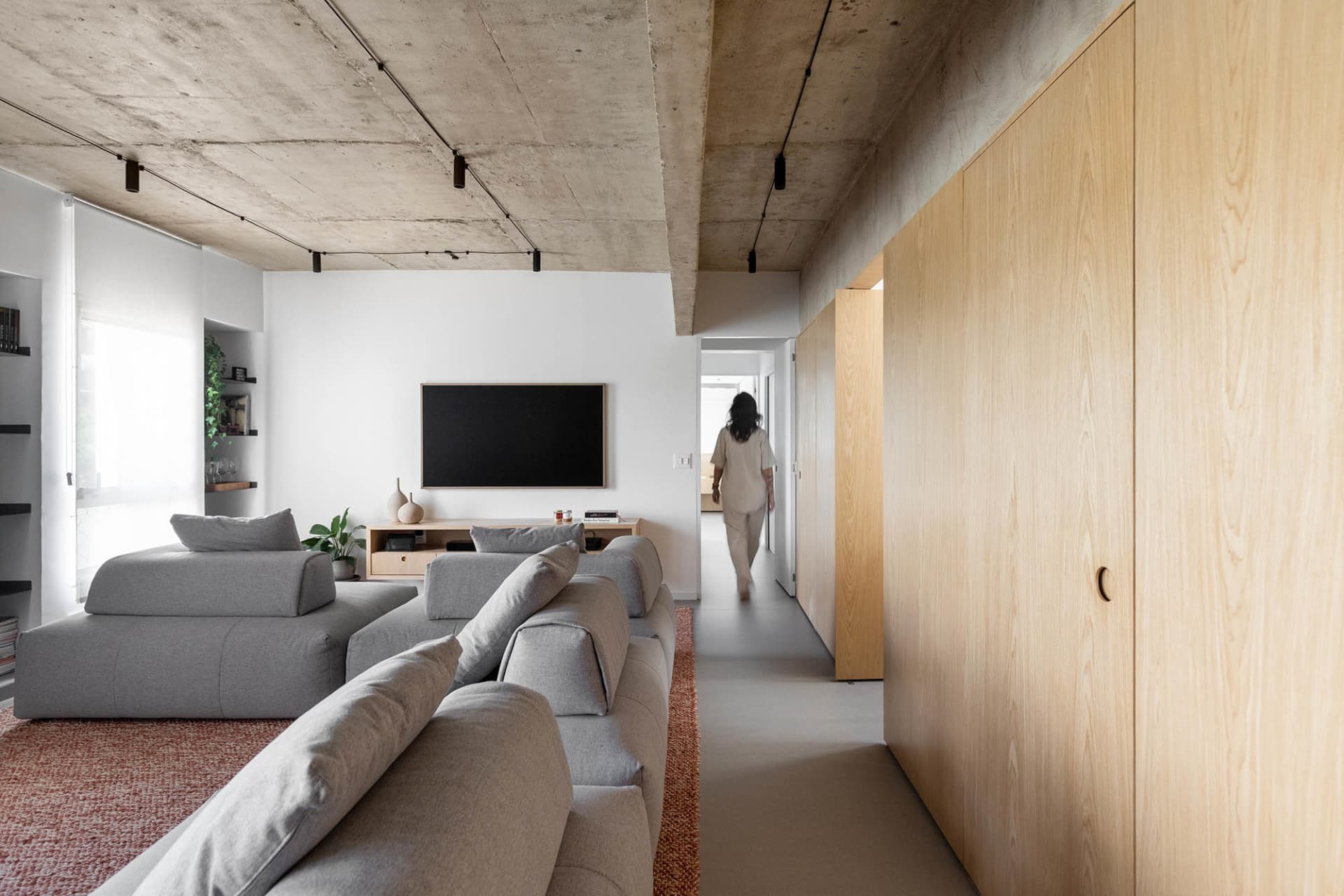 A comfortable open living area with a couch, chairs, TV, and potted plants, perfect for relaxation and socializing