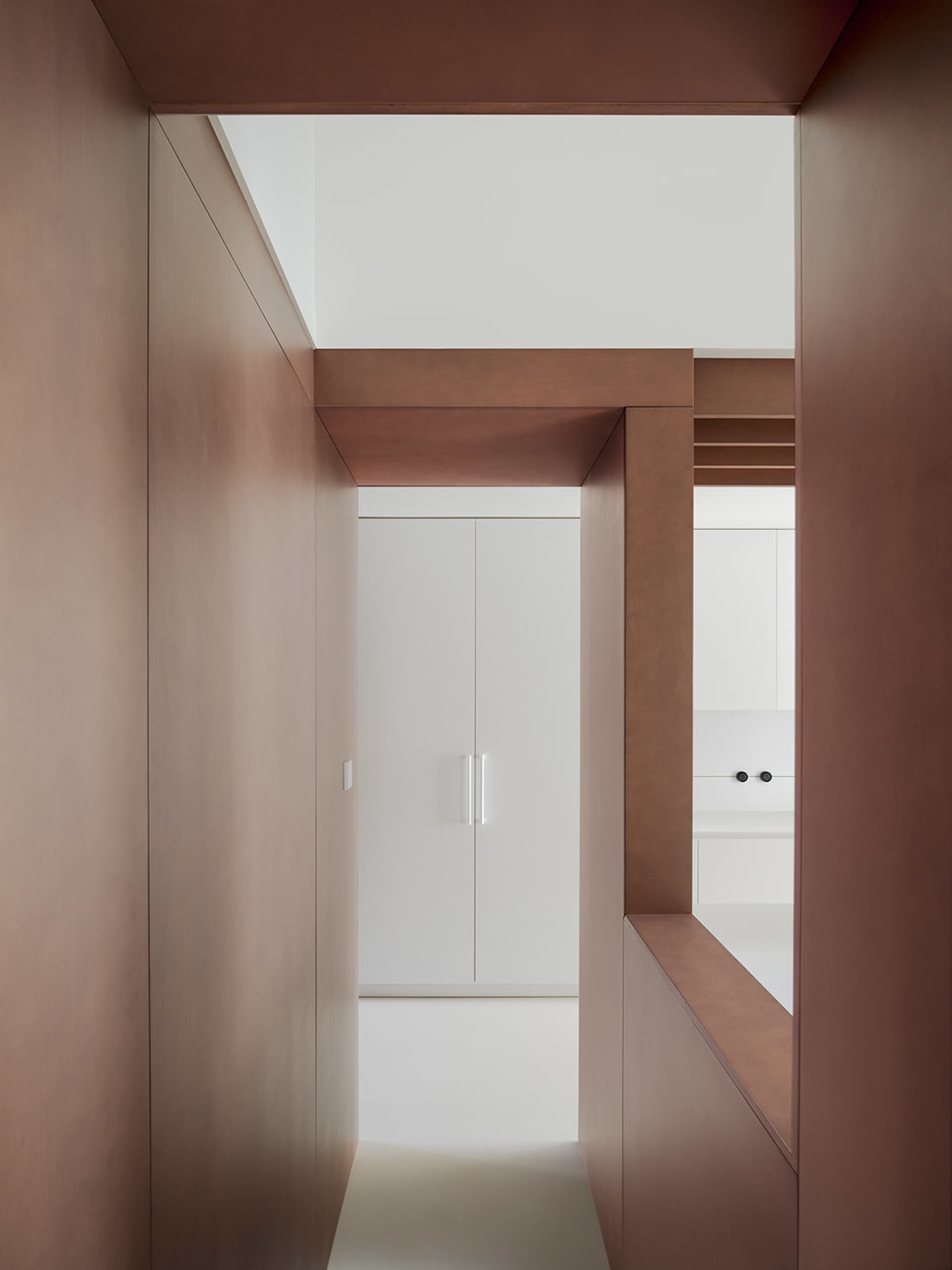 A modern kitchen with a white countertop, sink, refrigerator, and cabinets, giving off a clean and modern vibe